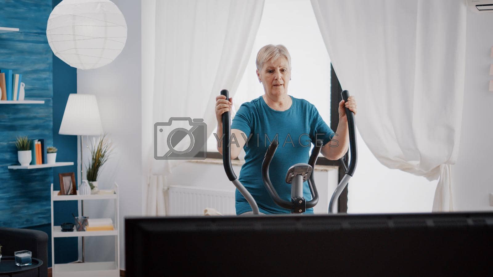 Royalty free image of Elder person training on electronic stationary bicycle by DCStudio