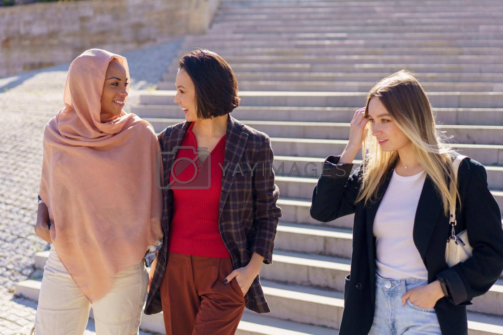 Royalty free image of Positive young diverse female friends walking downstairs in campus by javiindy