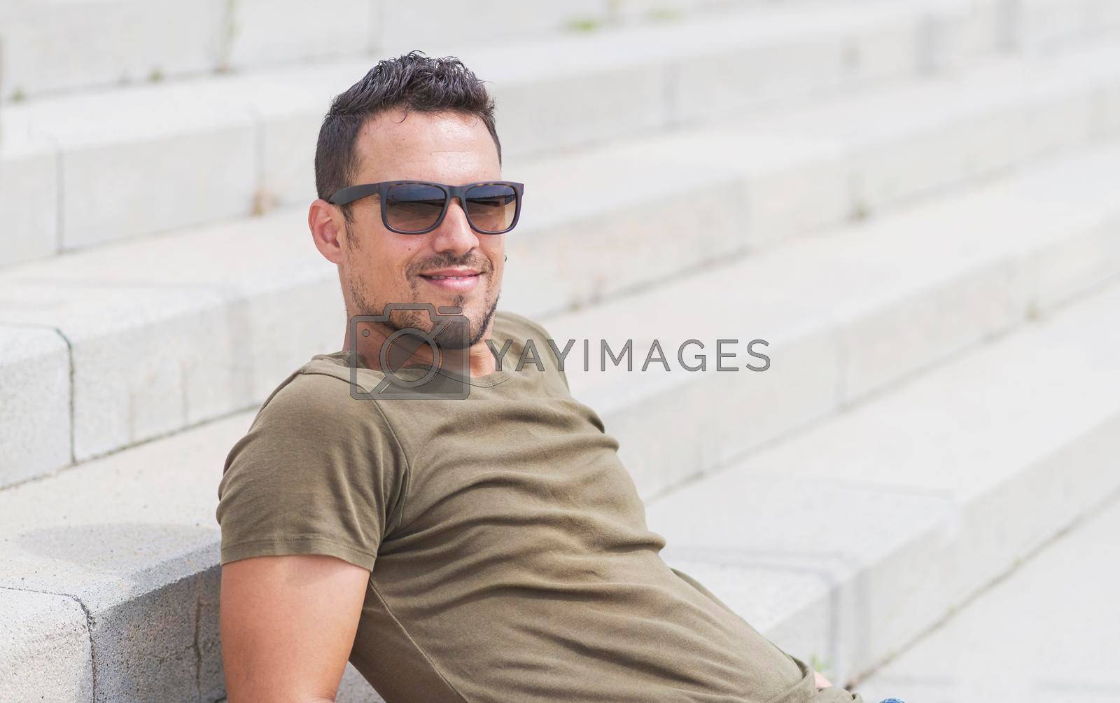 Royalty free image of Man sitting alone on steps. Handsome boy with sunglasses by raferto1973