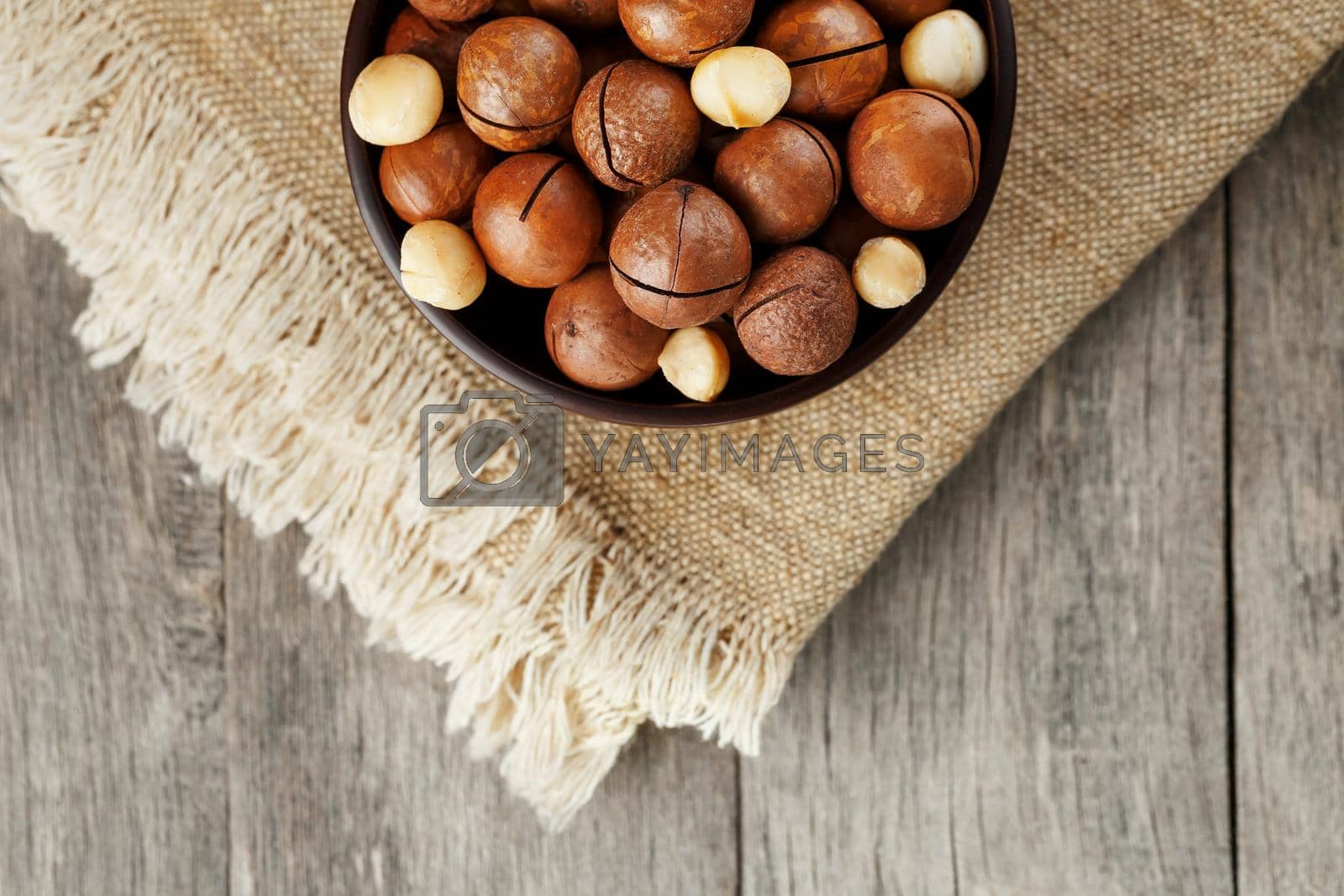 Royalty free image of Macadamia nut on wooden background with vintage cloth, concept of superfoods and healthy food by AlexGrec