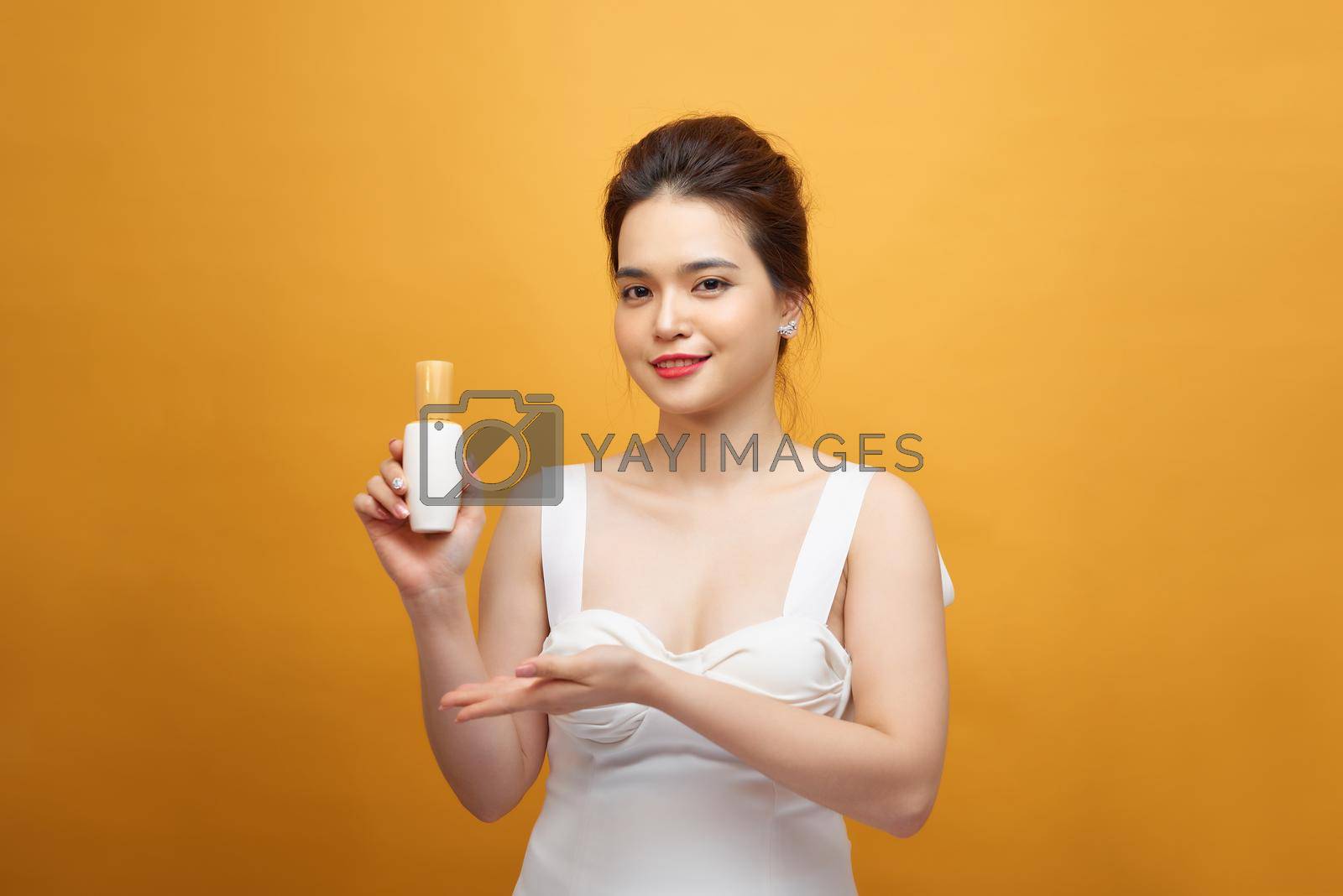 Asian young woman showing beauty product on hand 