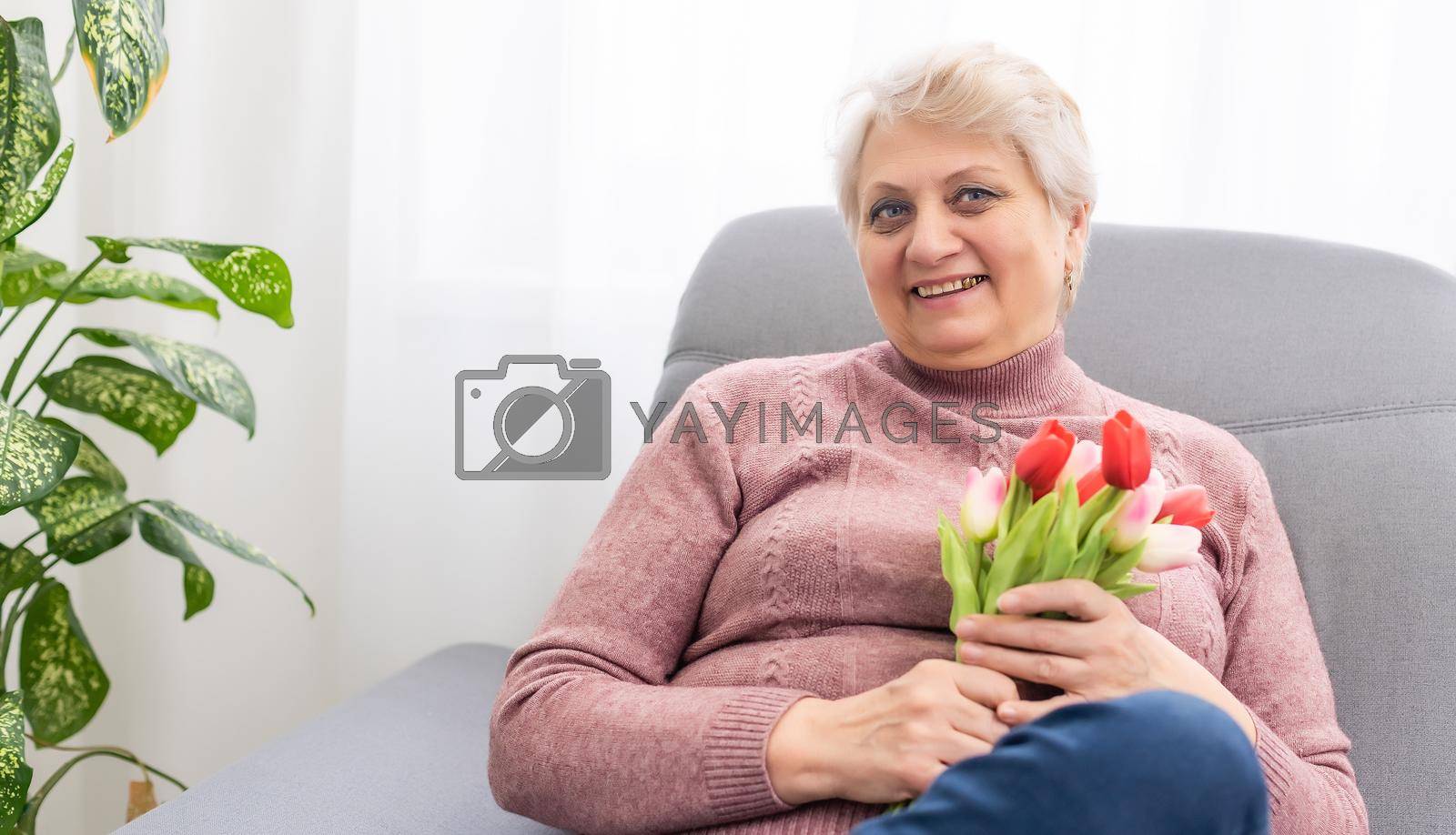 Royalty free image of A beautiful old lady smelling a bouquet of tulips by Andelov13