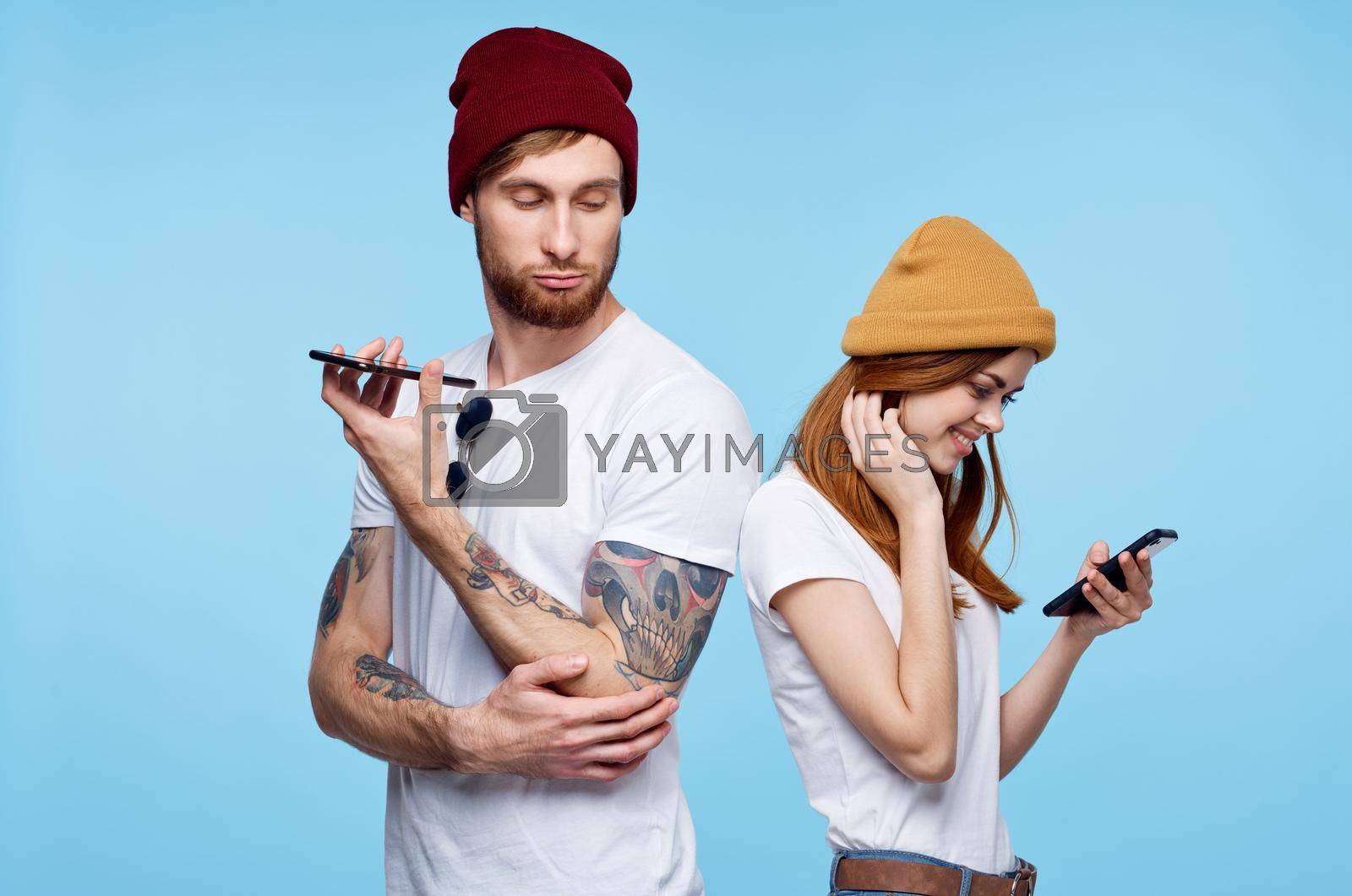 young couple in hats with phones in hands fashion communication. High quality photo