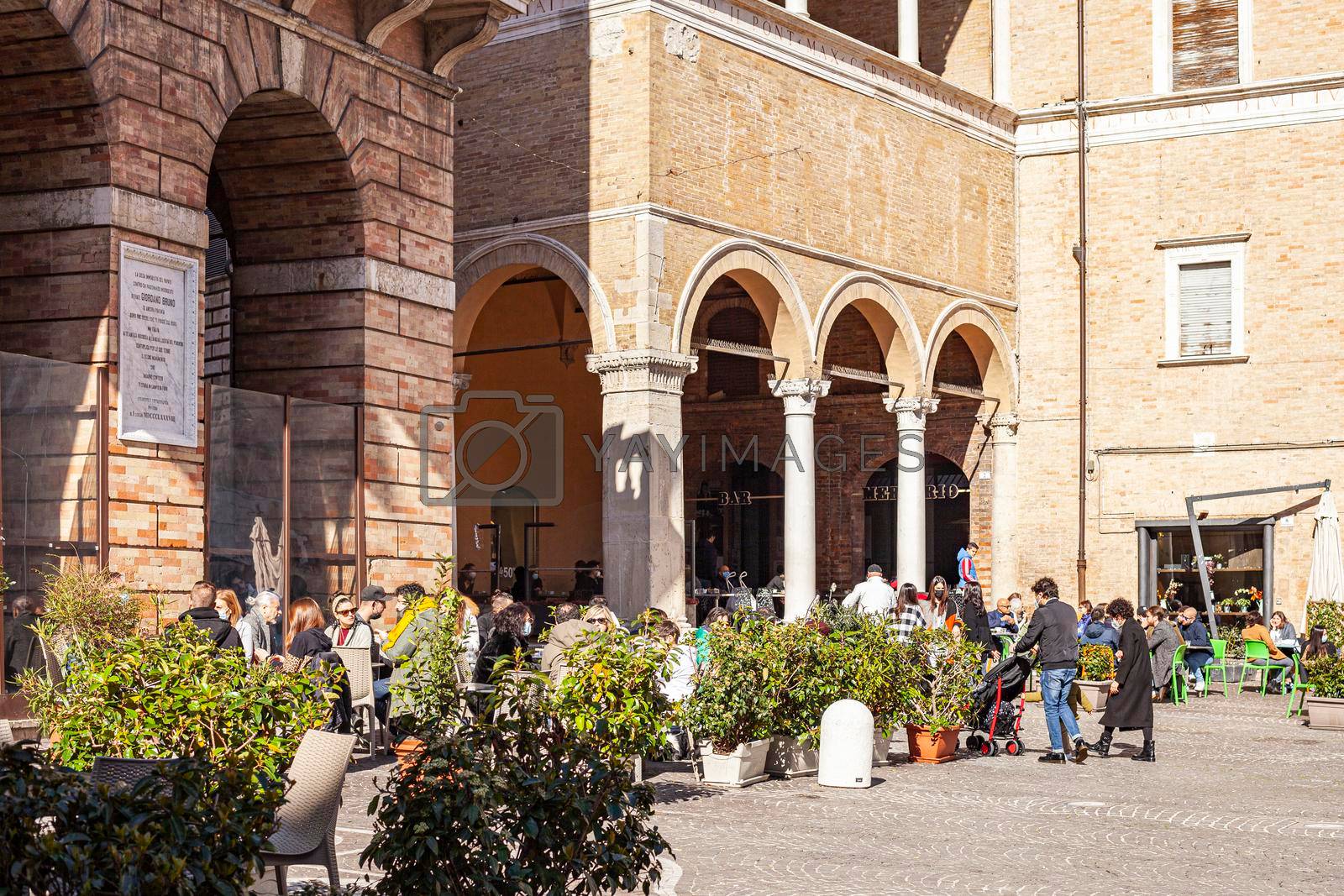Macerata, Italy - February 21, 2021: People enjoying sunny day and outdoor and resting in the restaurant, wolking on the street.