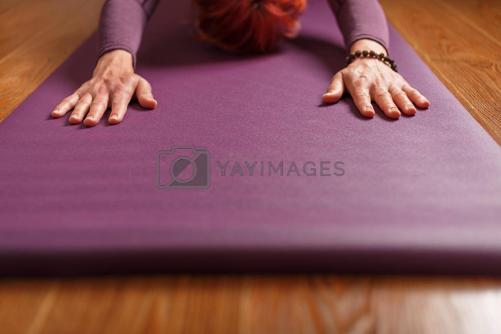 The girl does yoga in the asana stand on a lilac mat. Healthy lifestyle, asana and meditation practices