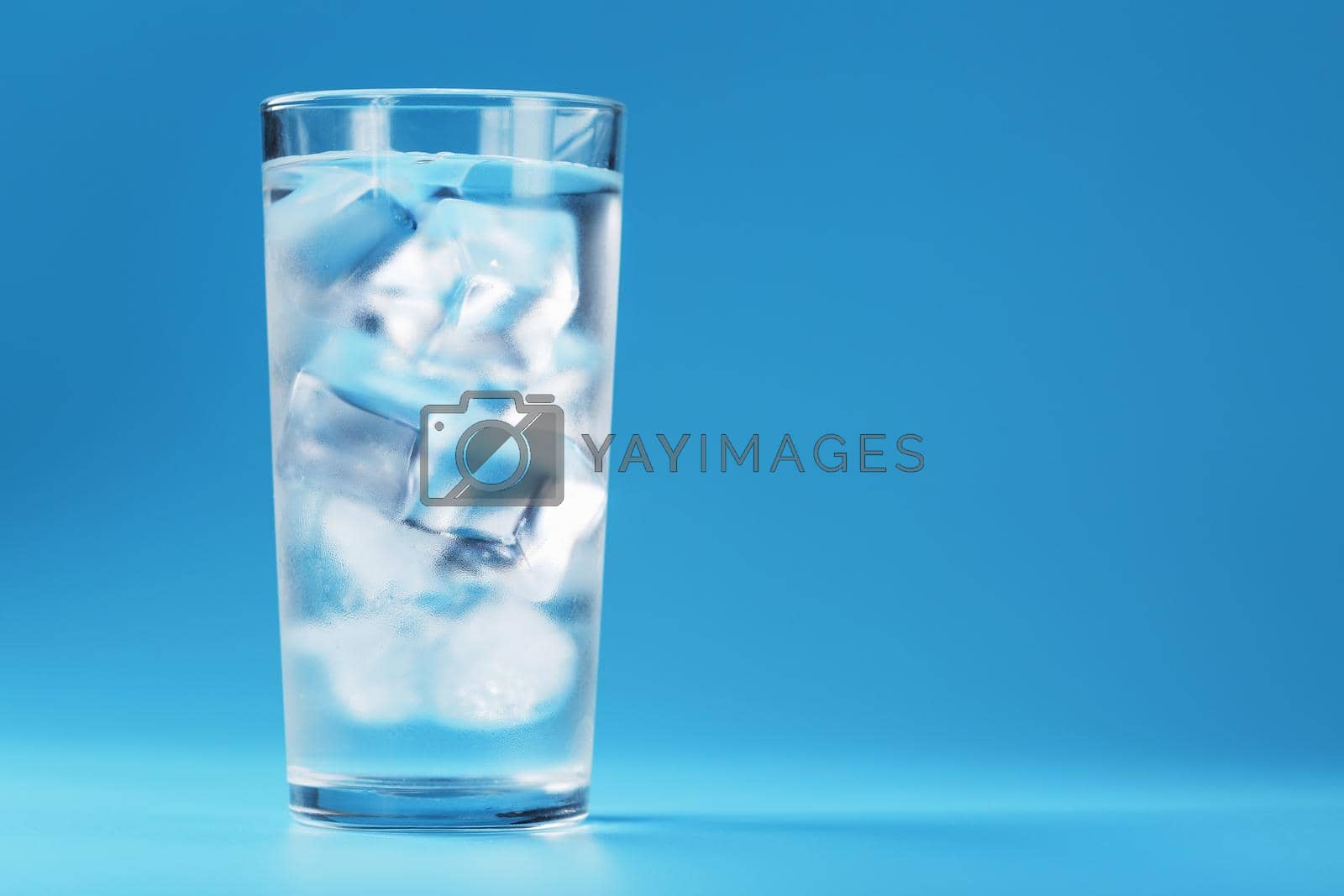 Royalty free image of Glass with water and ice cubes on a blue background by AlexGrec