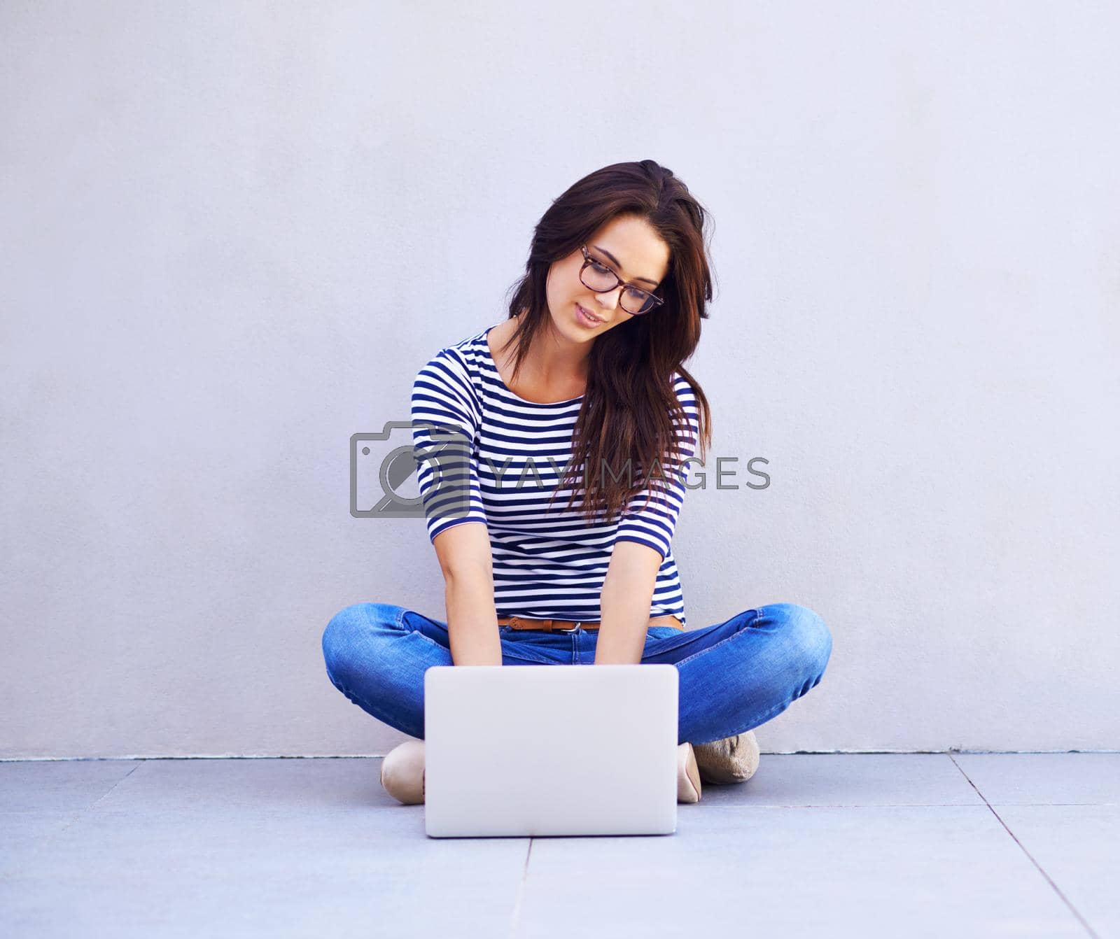Royalty free image of Just surfing the blog-o-sphere. Full length shot of an attractive young woman sitting cross legged using a laptop. by YuriArcurs