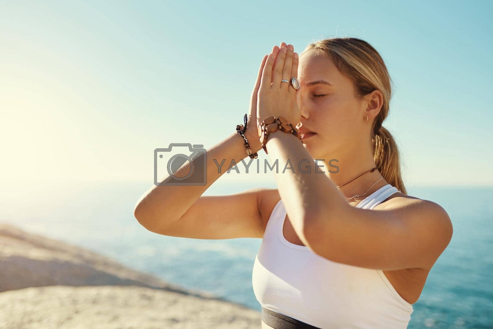 Shot of a young woman doing yoga at the beach