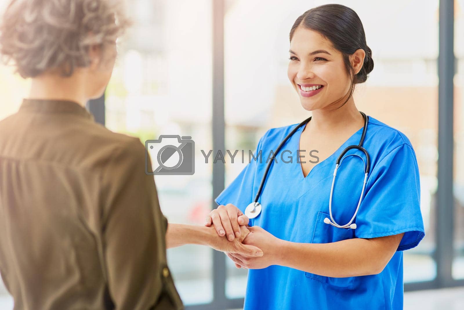 Shot of a kind young doctor holding her patients hand