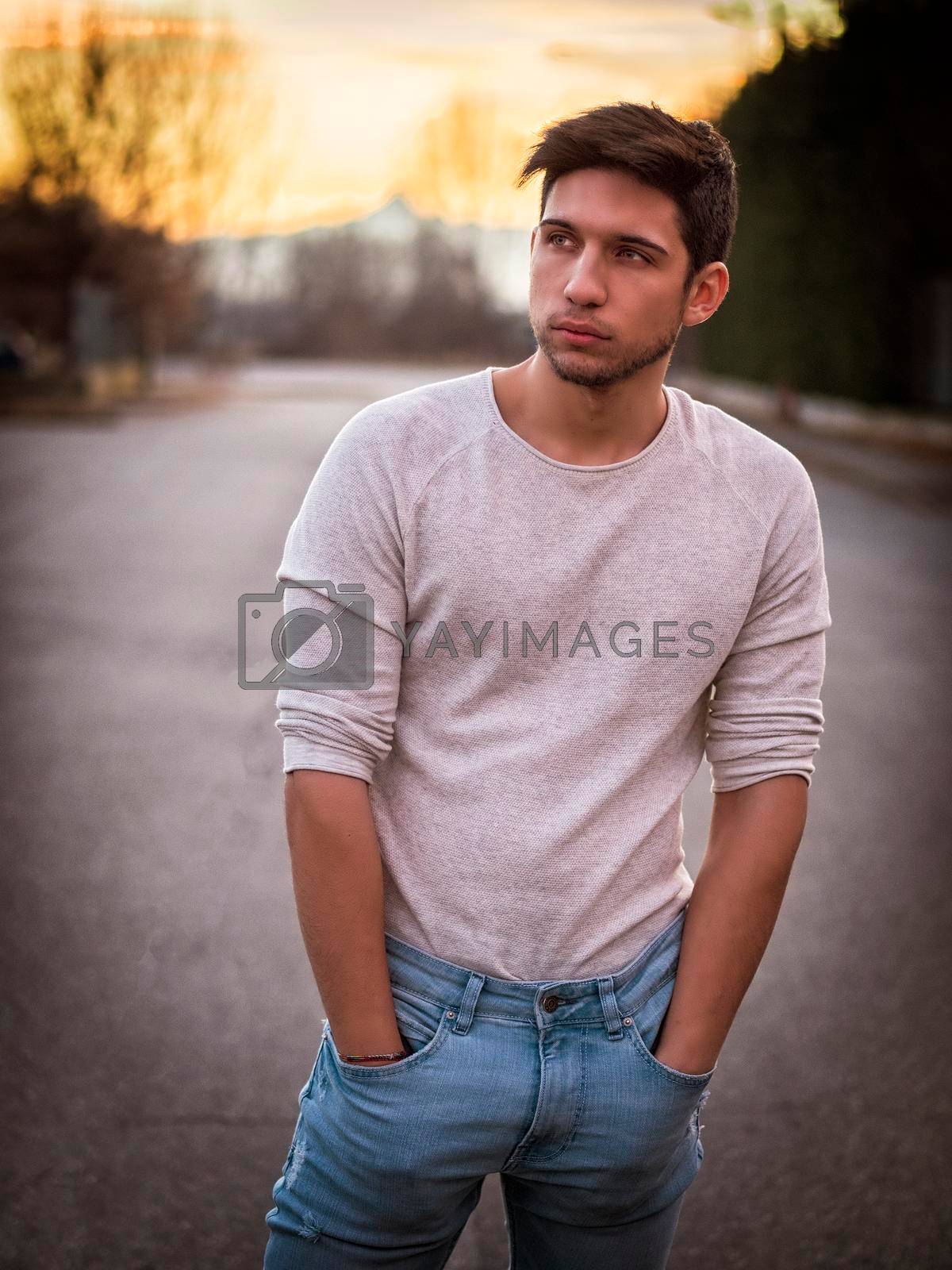 Royalty free image of Handsome young man in white sweater outdoor in street by artofphoto