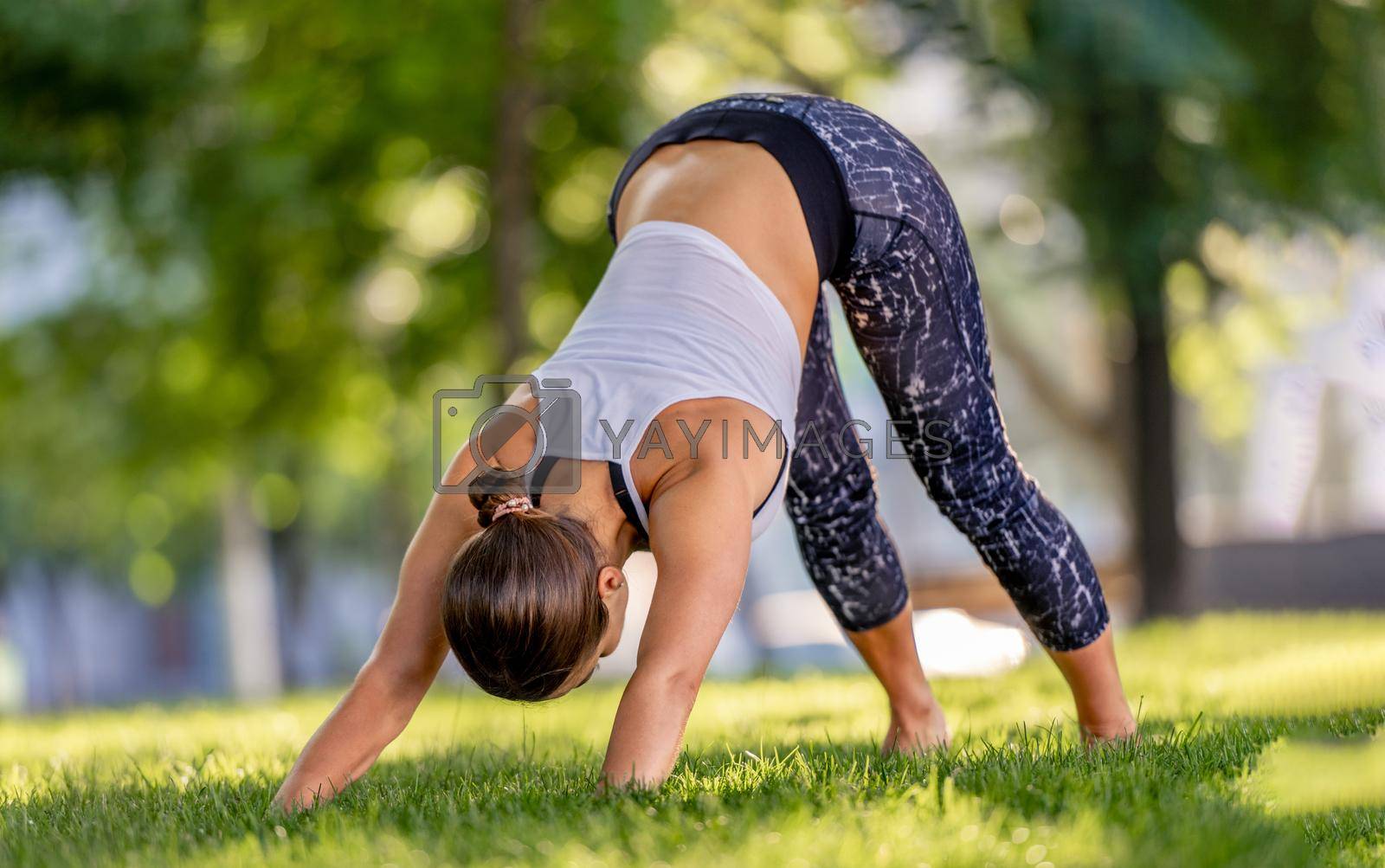 Sport girl doing yoga workout at nature in summertime. standing in pose and smiling. Young woman exercising and stretching outdoors in the morning