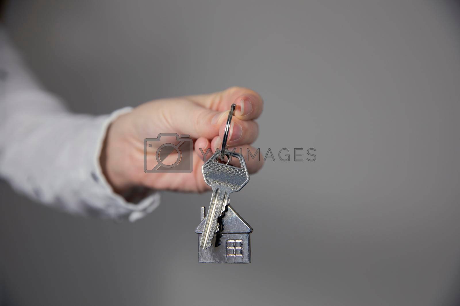 Real estate agent with house model and keys, selling house,property owner mortgage concept with copy space on gray background space for text