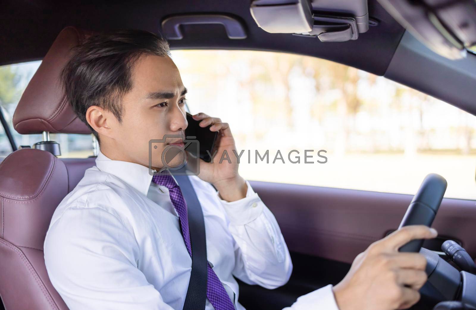 Young business man talking on the phoneand driving in the car