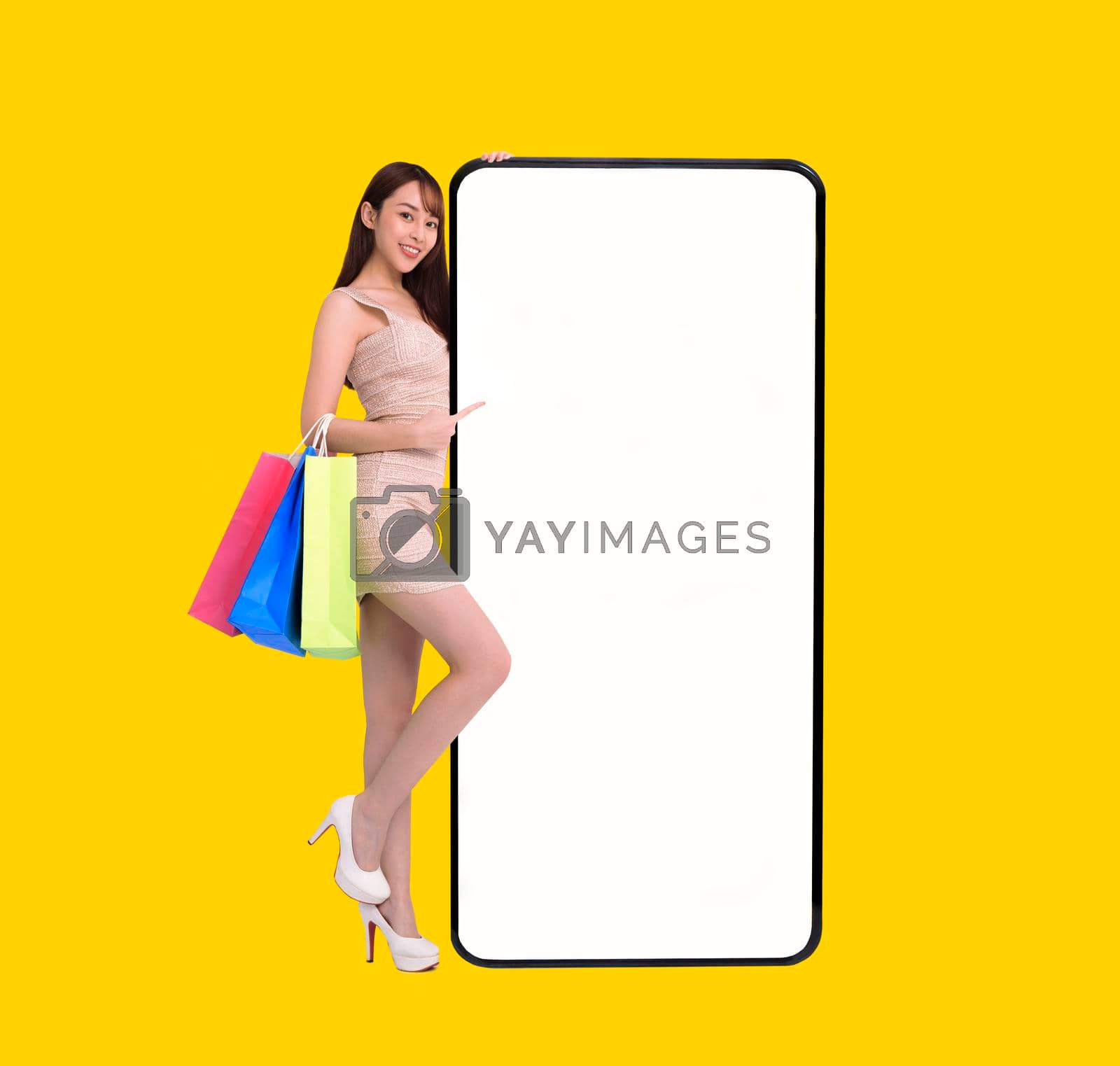 Royalty free image of Happy young woman standing and Leaning big Smartphone With Blank White Screen. shopping online with mobile phone concepts by tomwang