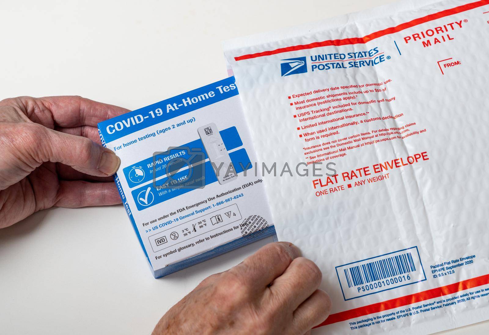 Morgantown, WV - 2 February 2022: Senior man opening the federally supplied at-home test for Covid-19 with US Postal service envelope