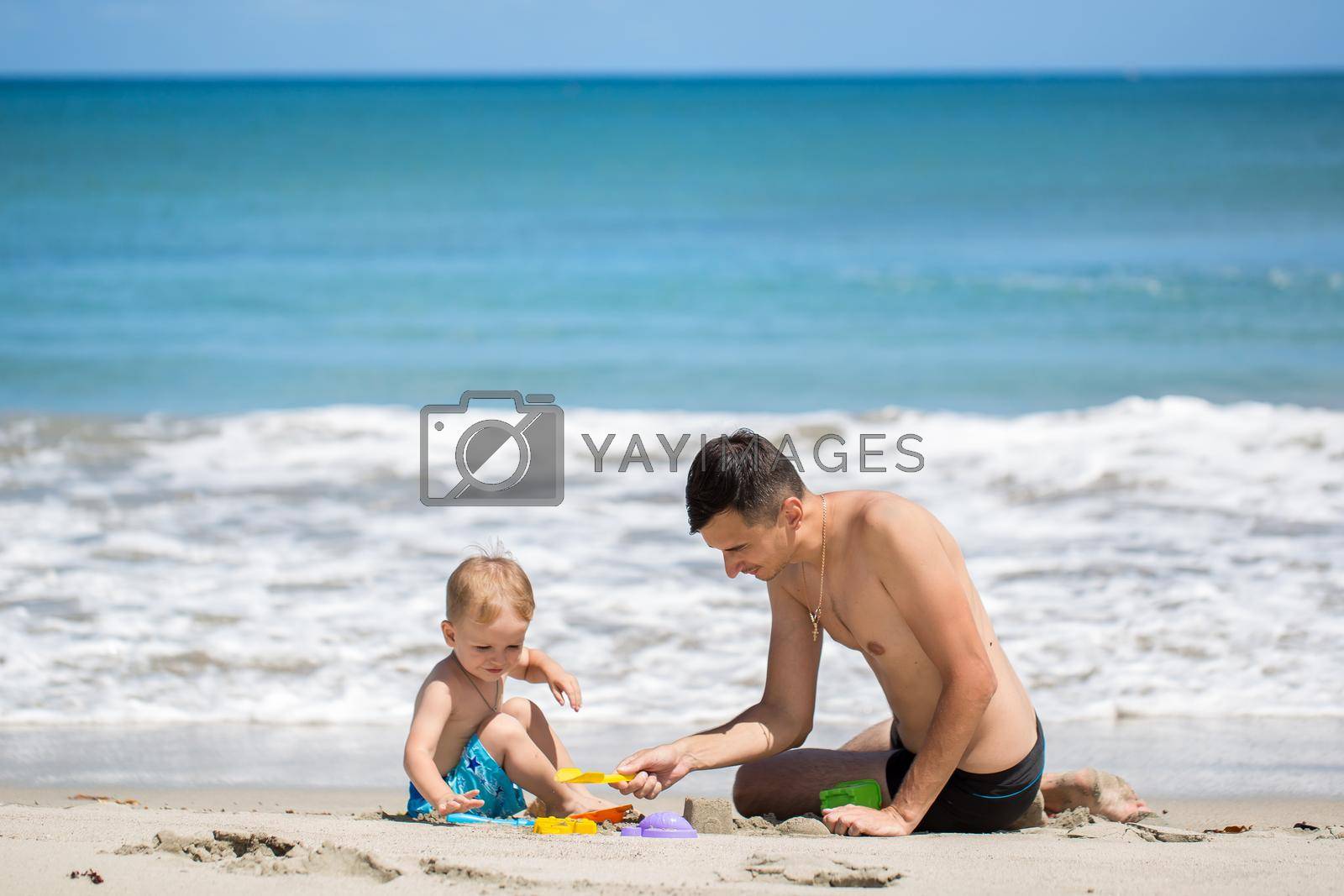 father and son building sand castle on beach