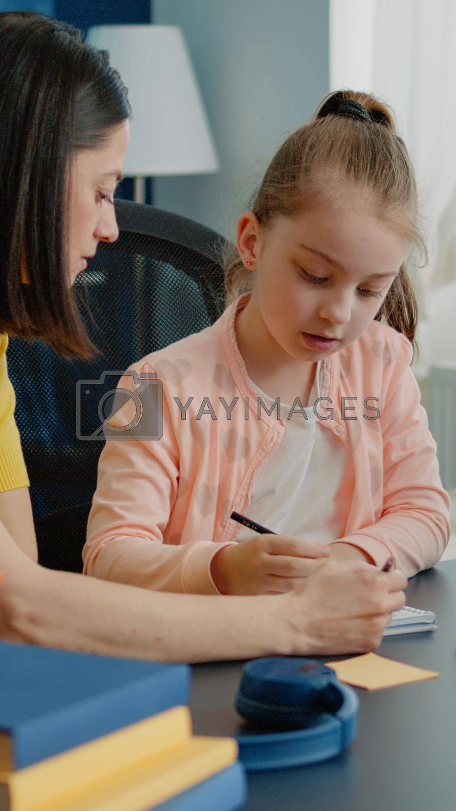 Mother and daughter doing homework together for online lesson on remote classroom. Parent helping little girl with school work and tasks for distance education on computer at home.