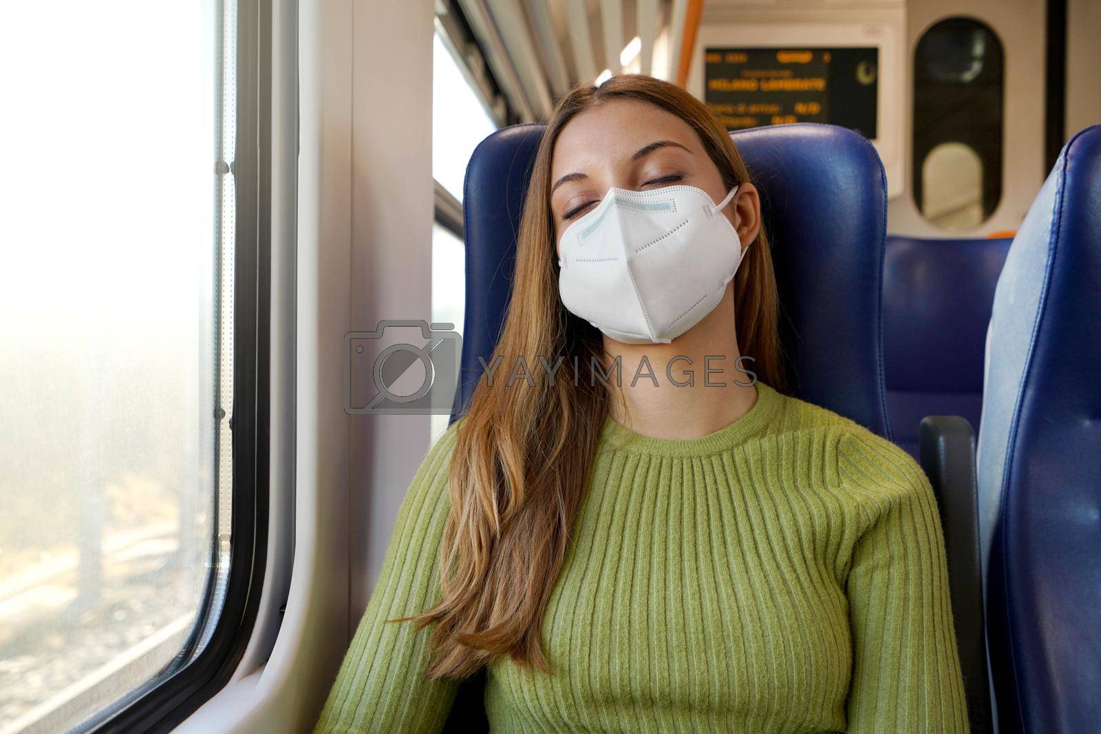 You can sleep peacefully. Relaxed beautiful woman with medical face mask sleeping sitting in the train. Train passenger traveling safely sitting in a seat and sleeping.