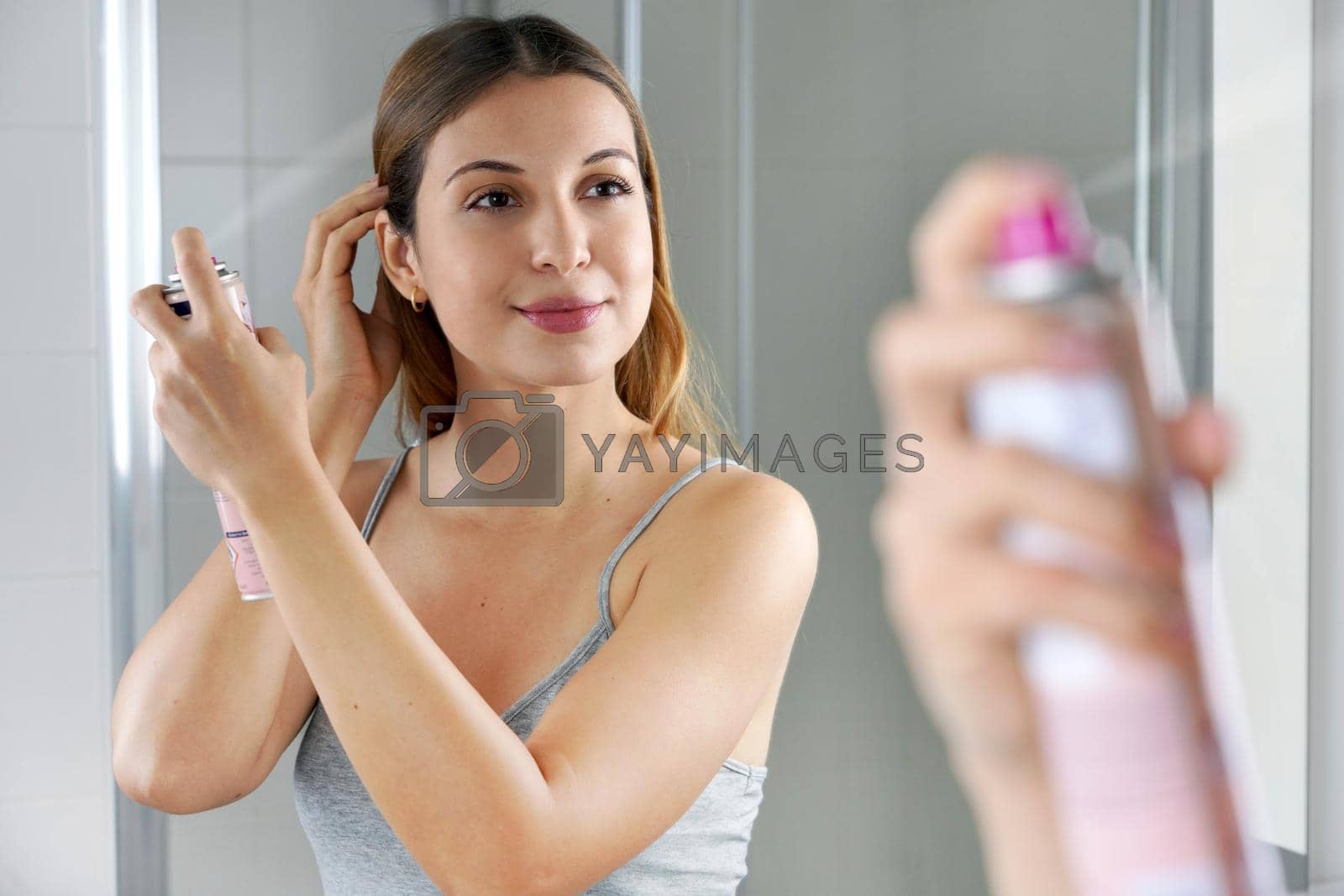 Beauty woman applying dry shampoo on her hair. Fast and easy way to keep hair clean with dry shampoo.