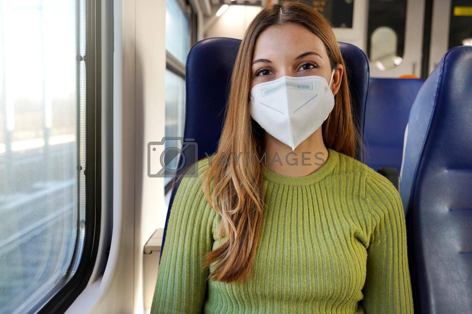 Urban Mobility and Safety in a COVID-19 World. Happy young woman wearing medical mask sitting on train looking at camera.