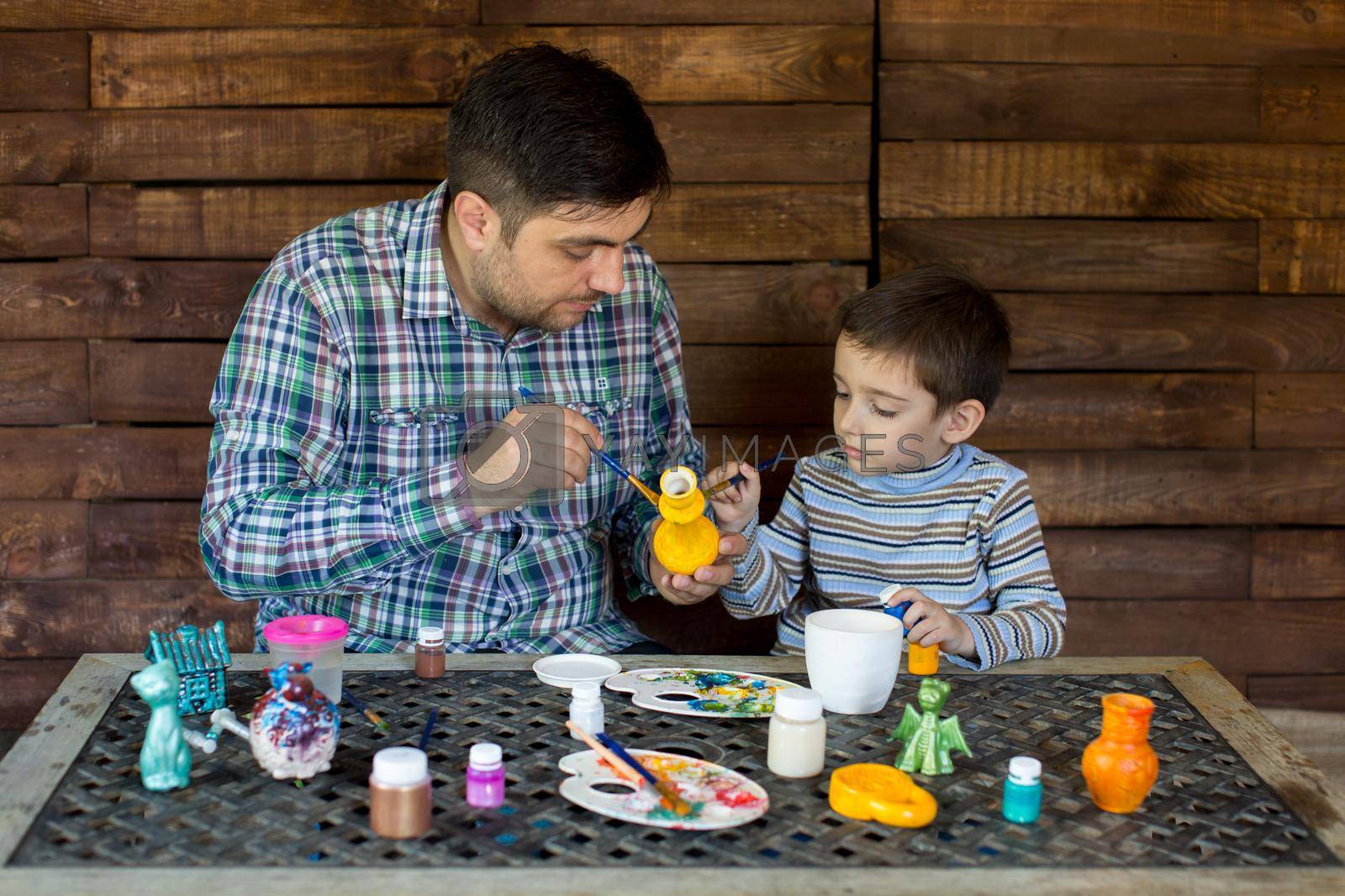 Father and son in the Studio of paint a vase.