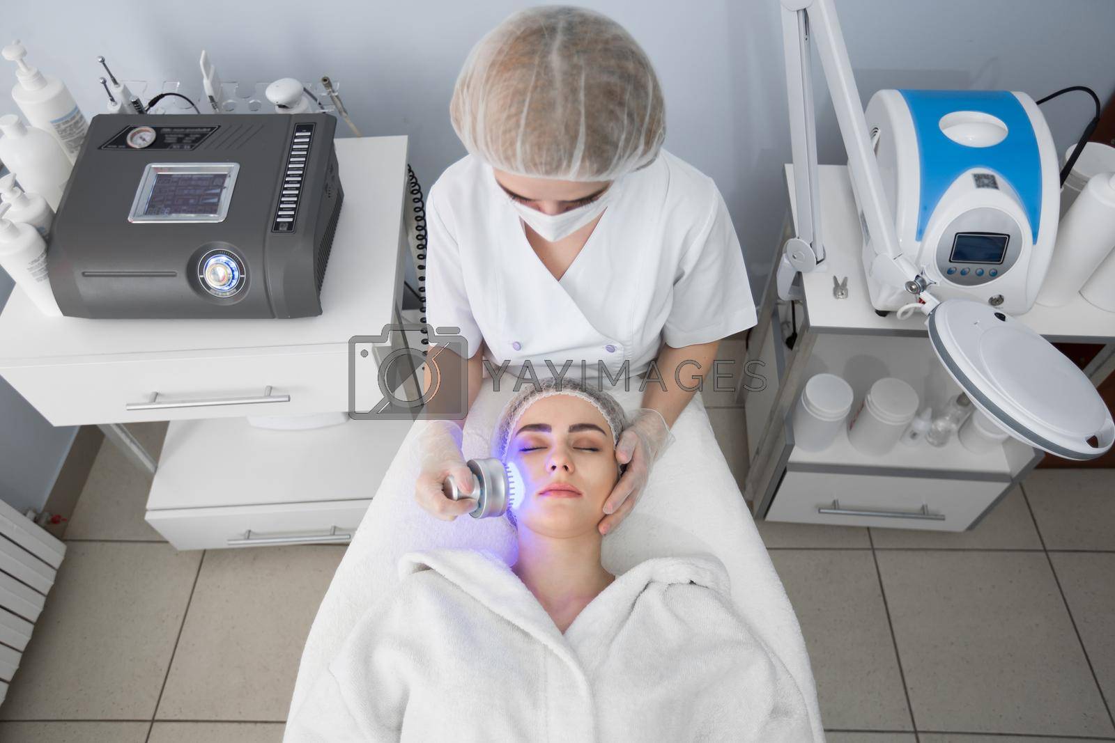 Ultrasonic massager. Light skin treatment, the woman in the beauty salon