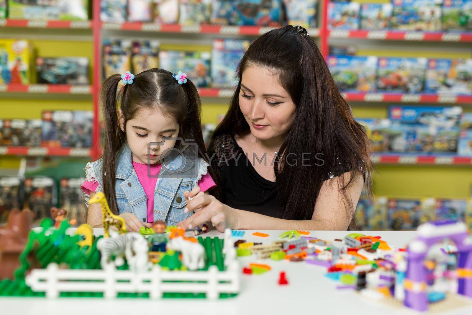 Mother with a little daughter playing with blocks