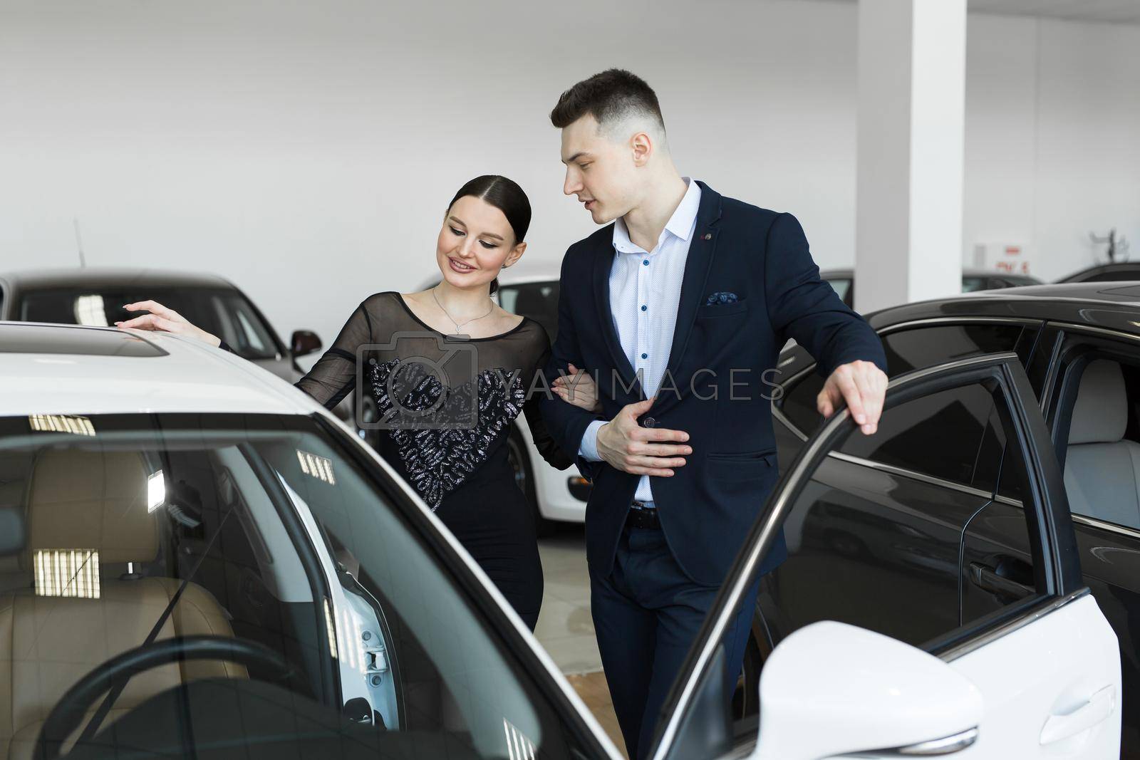 Royalty free image of A couple husband and wife choose a car to buy at a car dealership. by StudioPeace