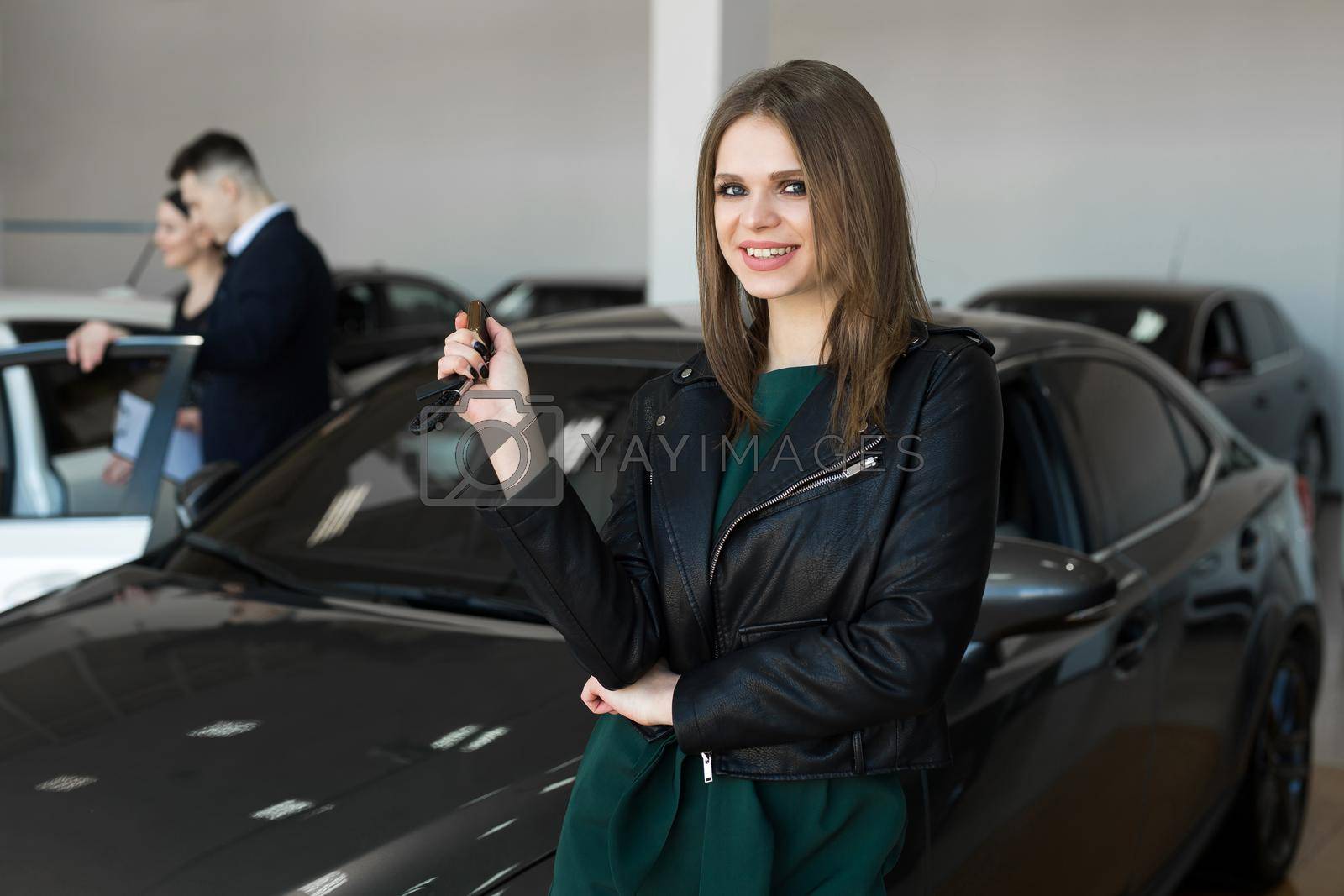 Royalty free image of Beautiful woman or car salesman stand holding a new car remote key in a car showroom. by StudioPeace