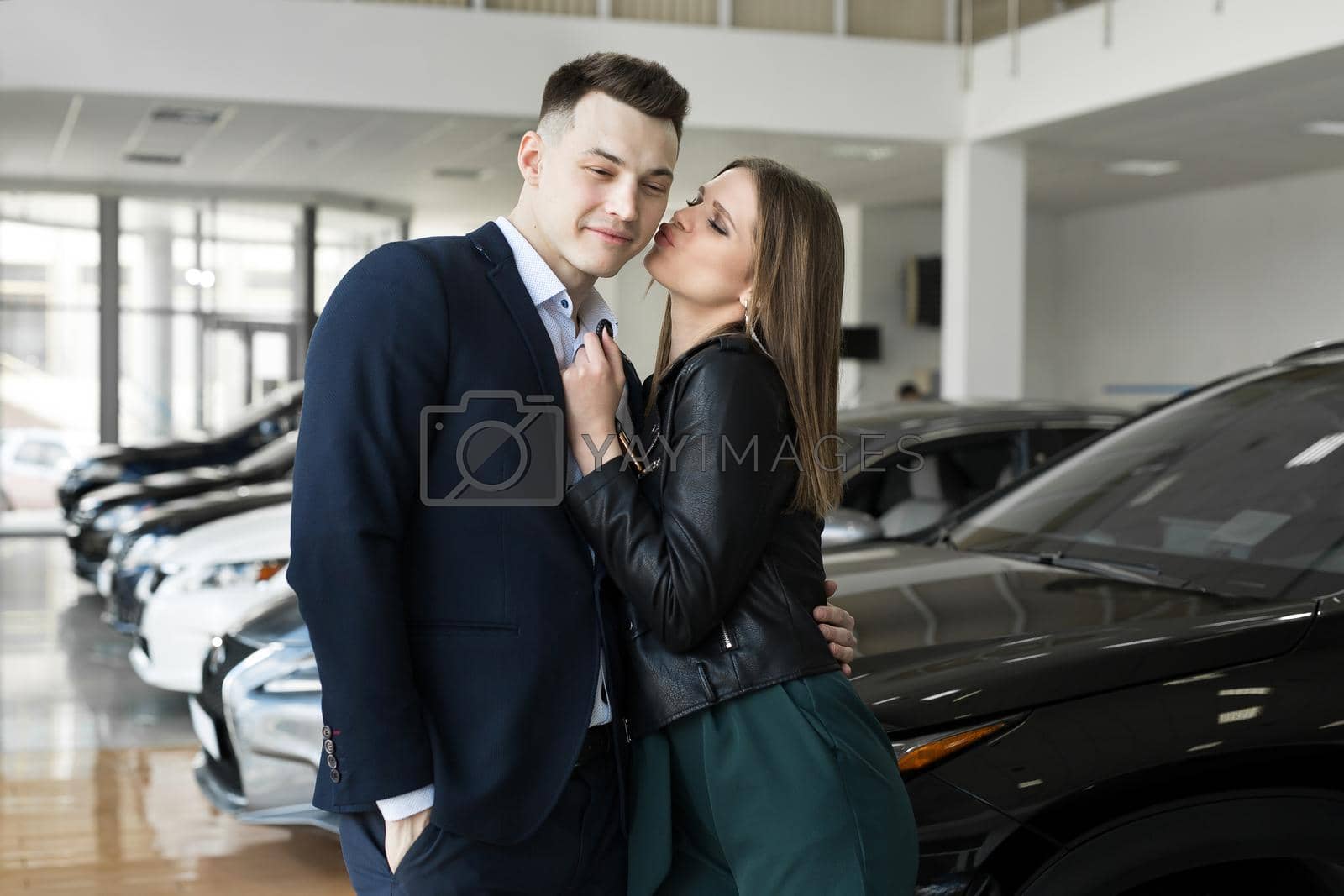 Royalty free image of A couple of men and women are happy to buy a new car in a car dealership. by StudioPeace