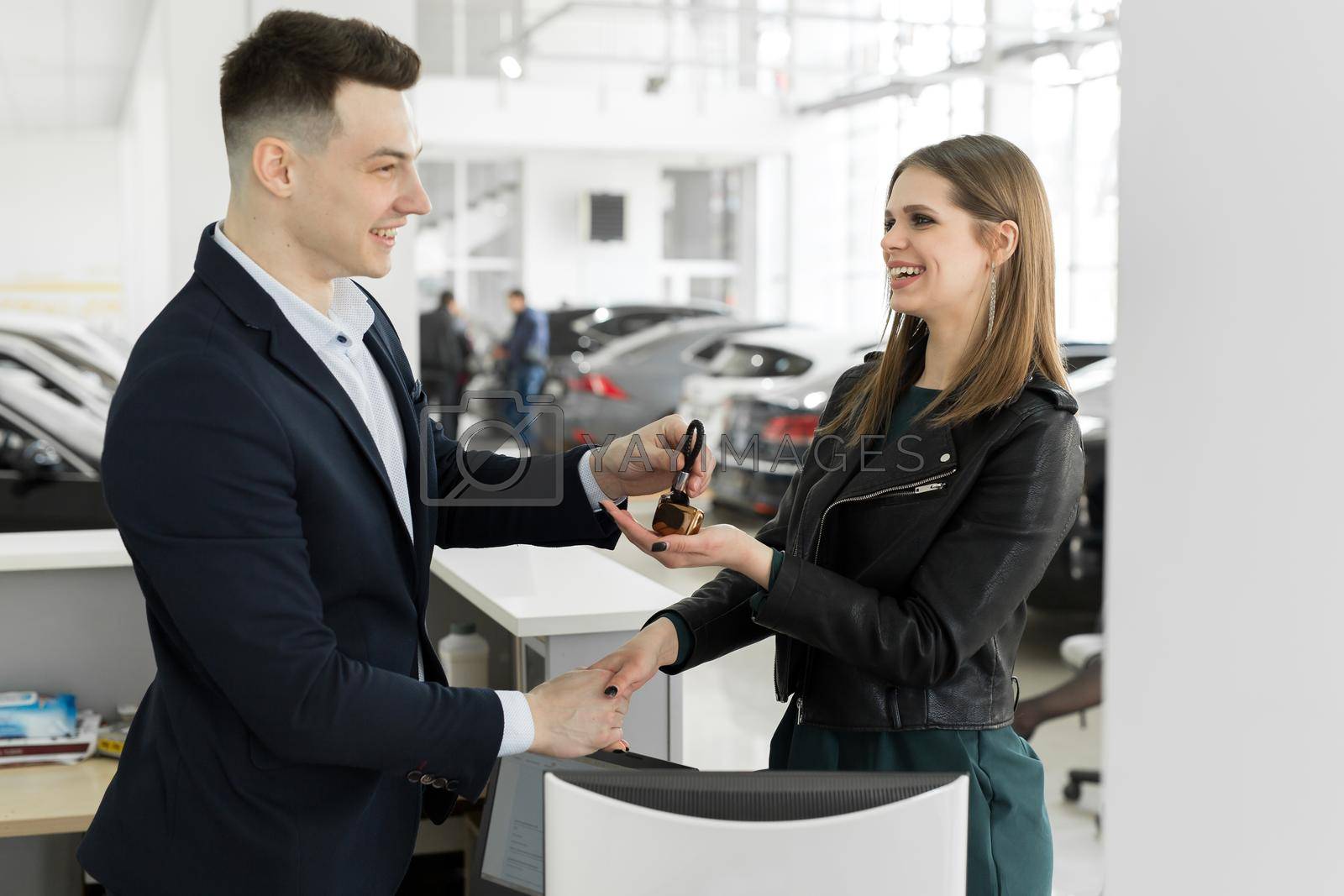 Royalty free image of Car rental and Insurance concept, Young salesman receiving money and giving car's key to customer after sign agreement contract with approved good deal for rent or purchase by StudioPeace