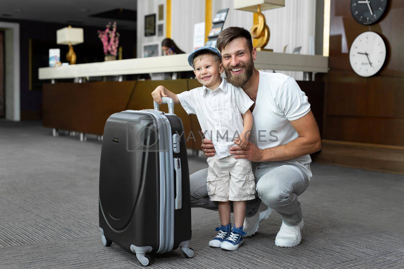 Father and son with a suitcase at the hotel reception.