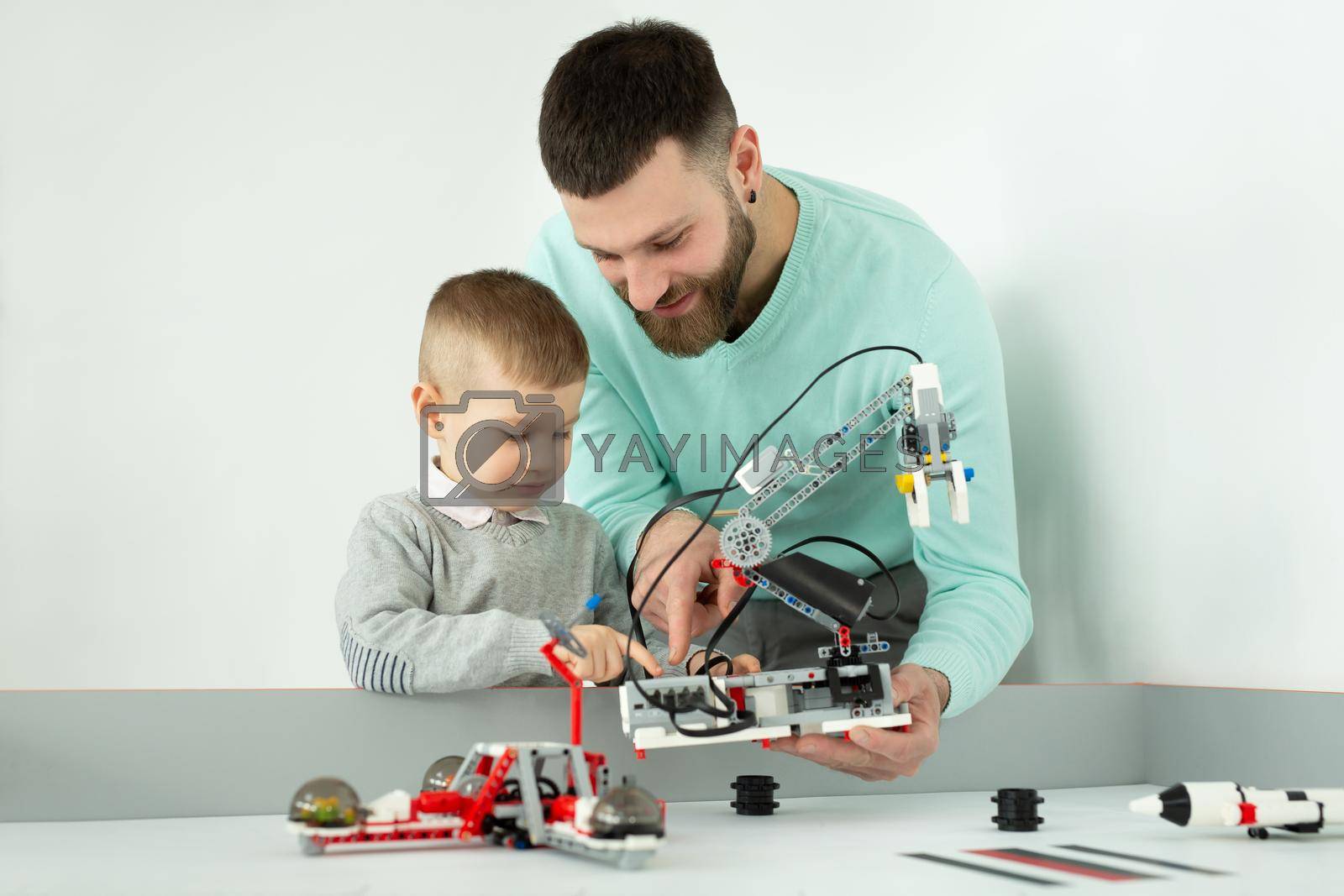 Young father and son create a robot in a robotics club.