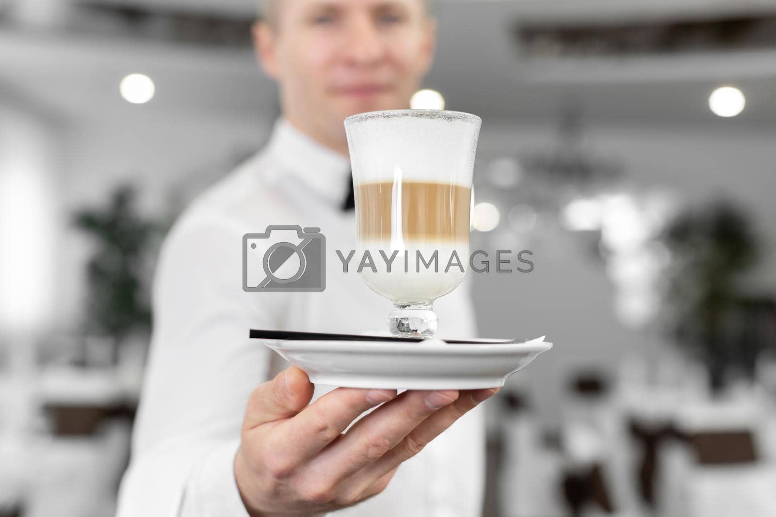 Royalty free image of Close-up of a latte in the hands of a male waiter by StudioPeace
