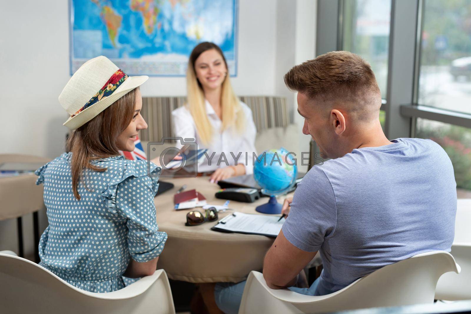 Royalty free image of Woman travel agent gives a couple passports with plane tickets in travel agency by StudioPeace