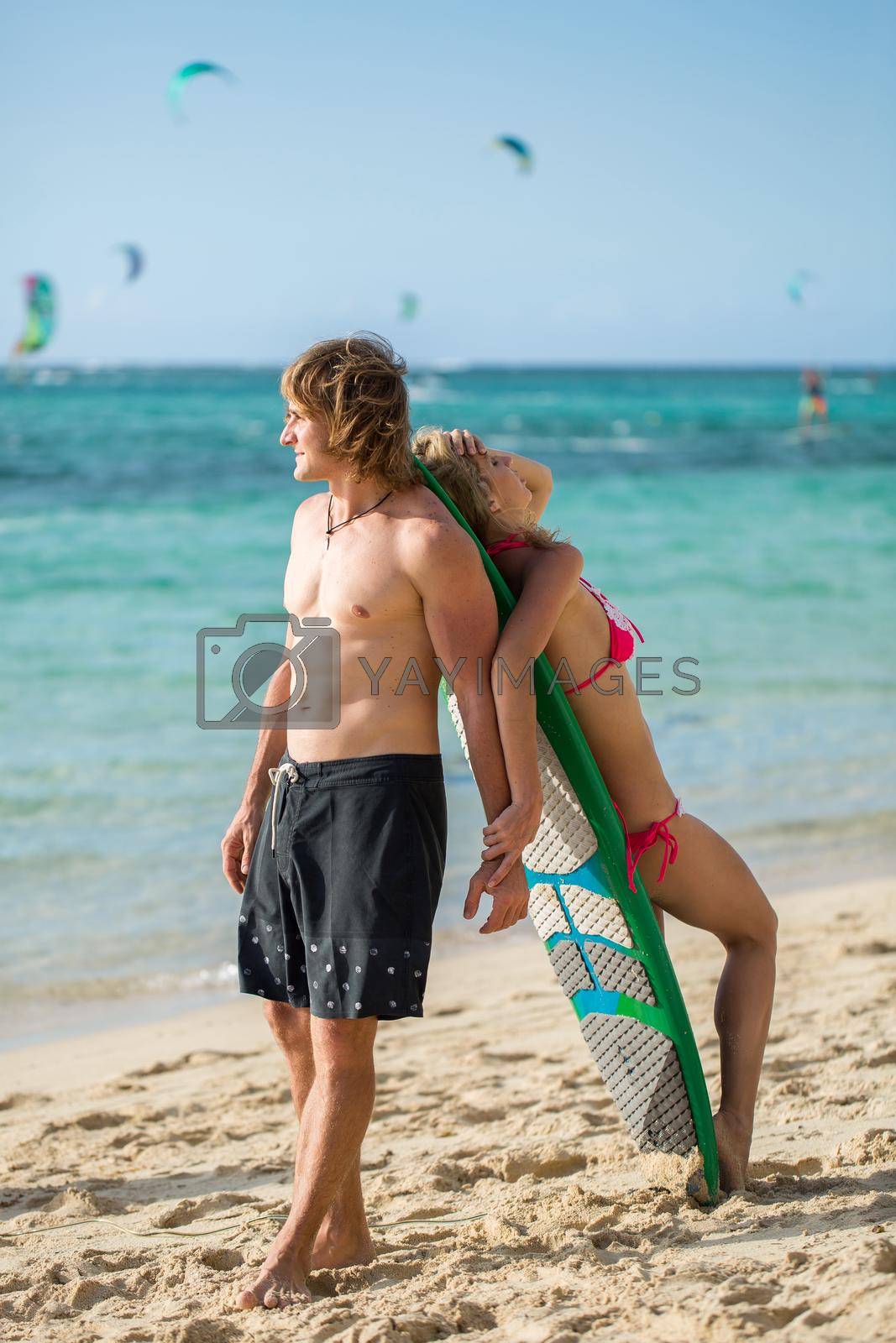 Young couple on beach with surfboard in arm. Surfing and outdoor sport lifestyle concept.