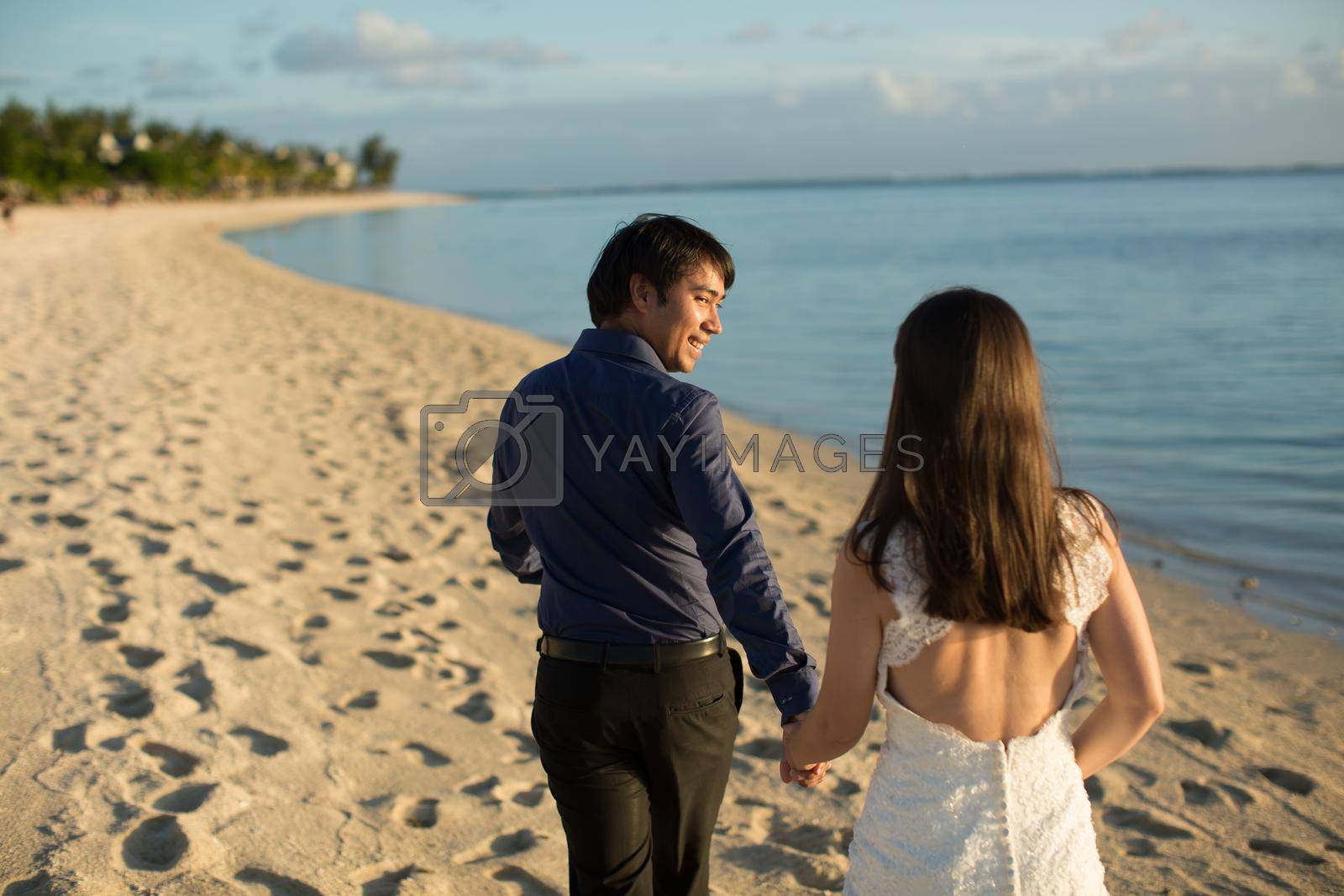 Royalty free image of bride and groom walking on the beach of Mauritius. by StudioPeace