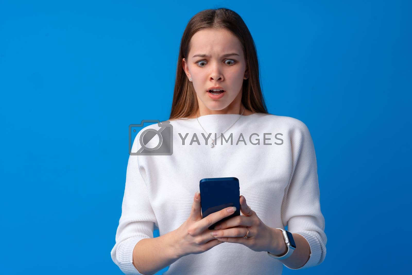 Royalty free image of Portrait of a teen young girl using smartphone over blue background by Fabrikasimf