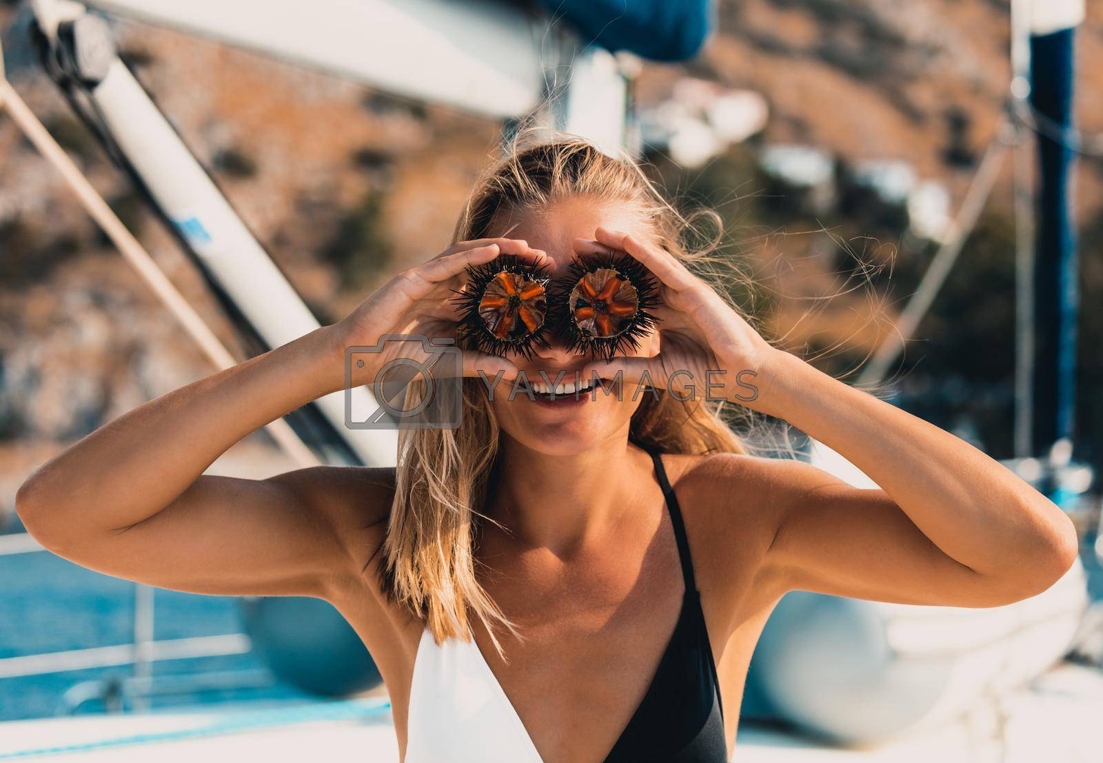 Portrait of a Cute Happy Girl Having Fun. Holding Two Half of a Sea Urchin on Eyes. Laughing and Enjoying Summer Trip on a Sailboat in Greece.