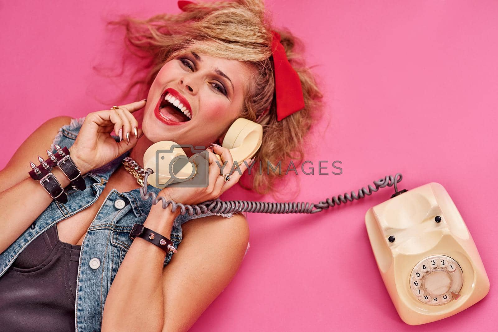 Royalty free image of Everyone had so much fun in the 80s. Studio shot of a young woman holding a telephone while wearing 80s clothing. by YuriArcurs