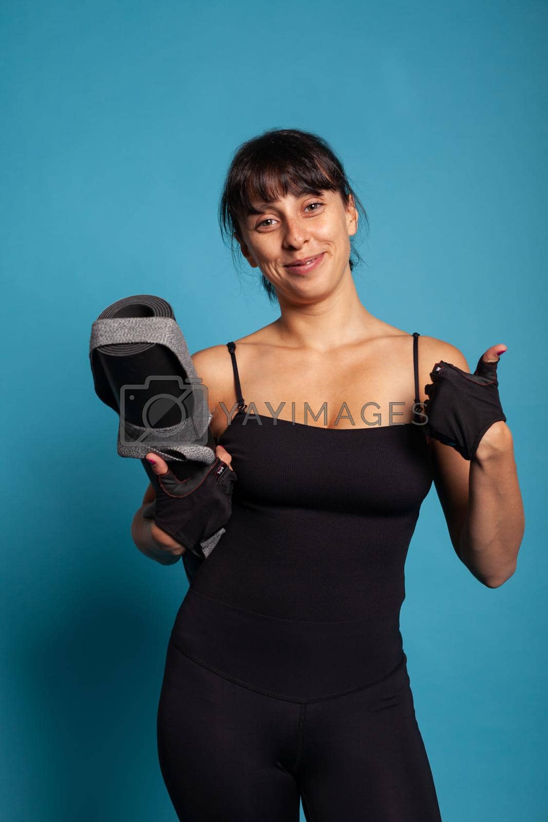 Portrait of athletic fit woman holding yoga mat before start working at fitness workout in studio. Personal trainer practicing gym exercices stretching body muscles working at healthy lifestyle