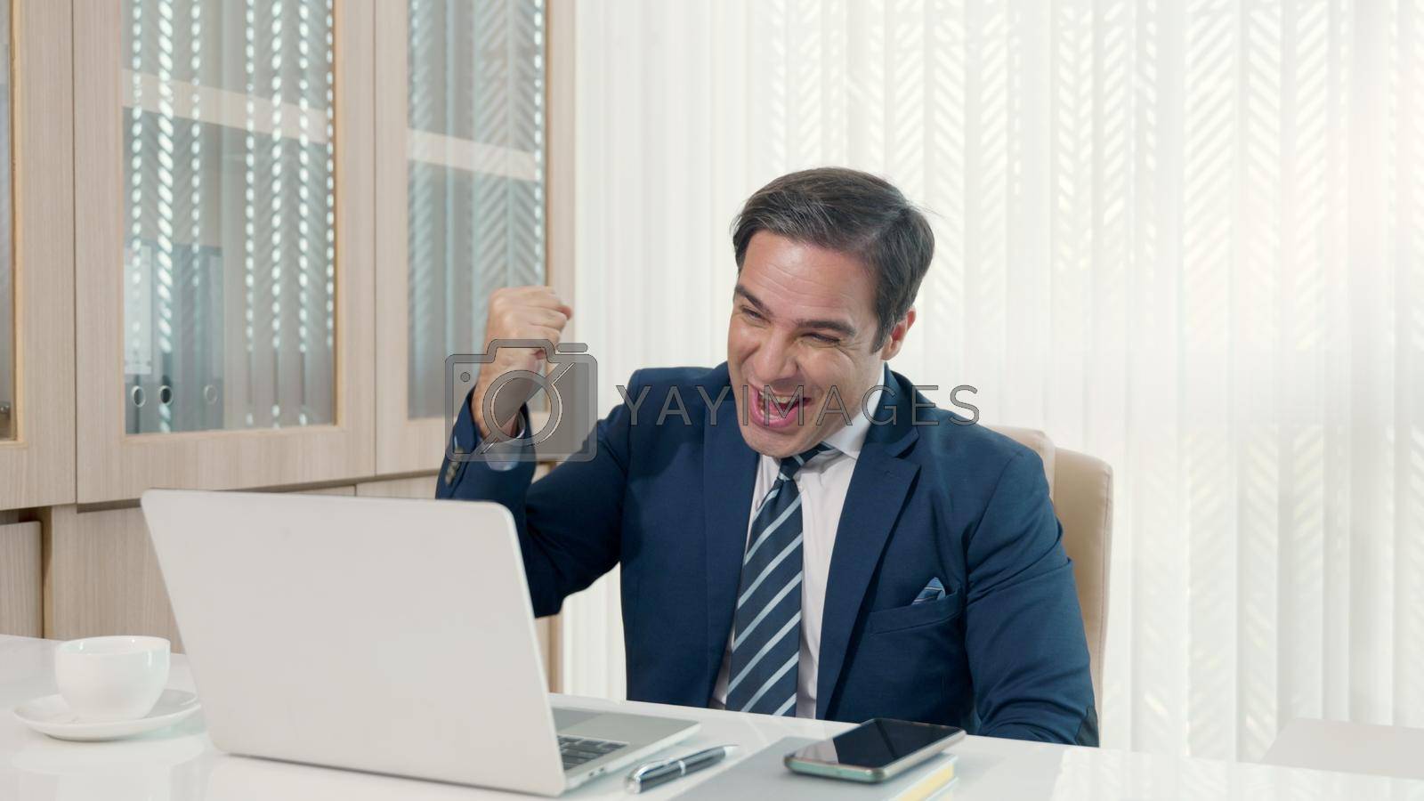 Business man sitting using laptop study online work at his desk success celebration at office, Smiling happy businessman cheerful in casual office making phone call while working with laptop computer