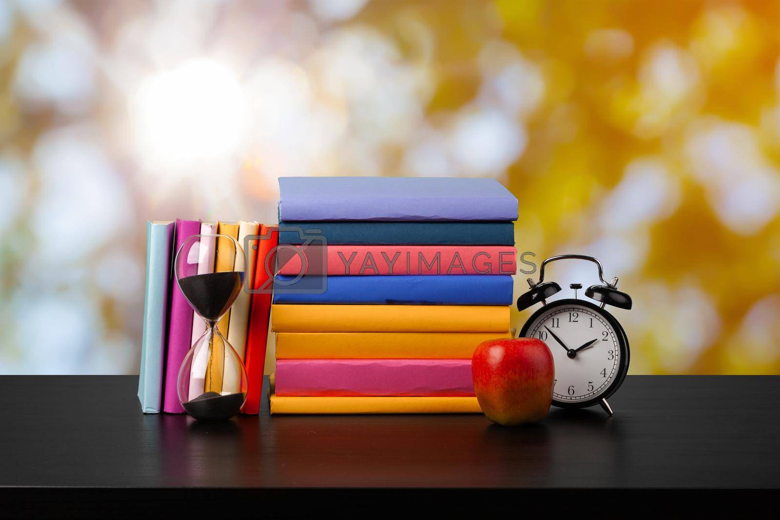 Royalty free image of Stack of books on wooden table against blurred background by Fabrikasimf