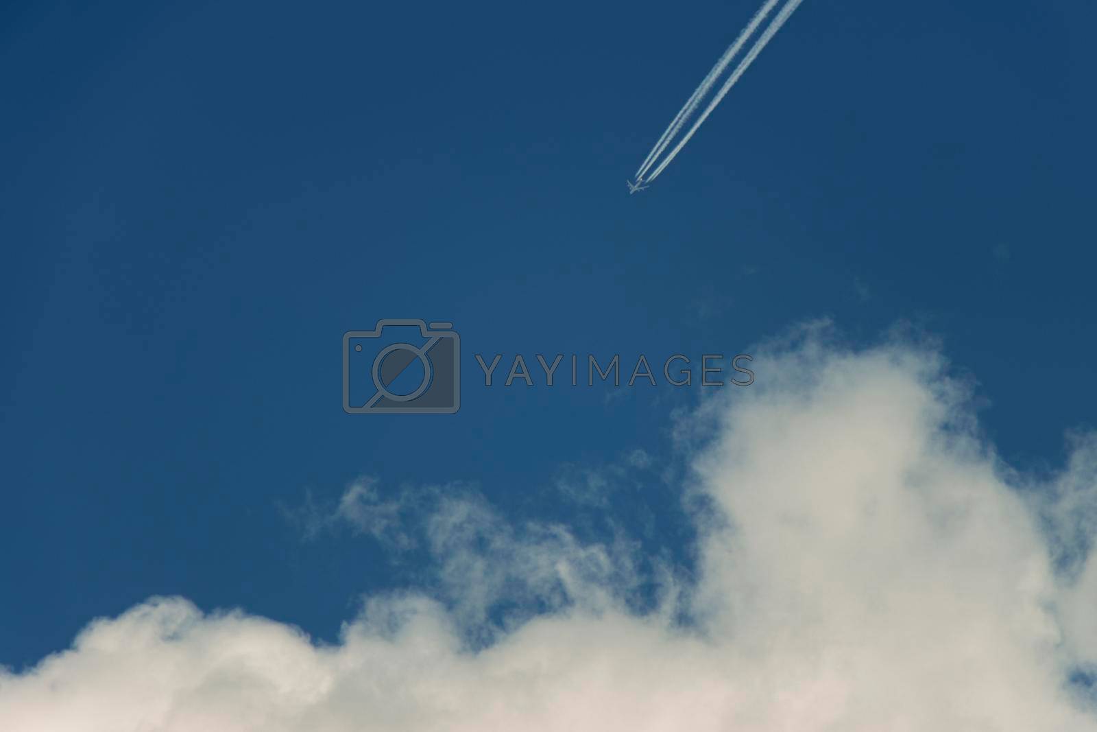 Airplane contrast against bright blue sky with a diagnonal straight condensation vapor trail, appearing as though it is heading towards a white candy floss cloud. Canon EOS 90D