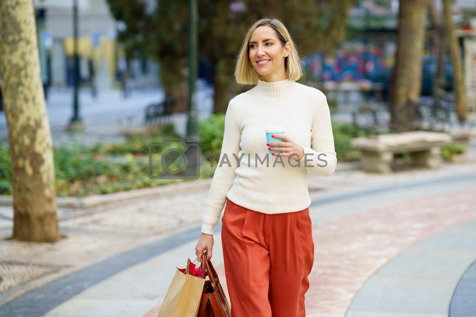 Royalty free image of Smiling woman with takeaway coffee carrying paper bag by javiindy
