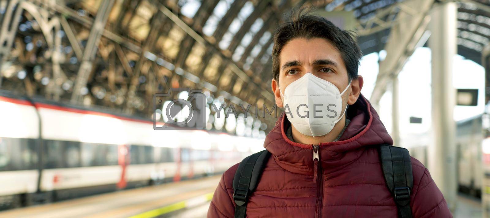 Royalty free image of Banner panorama of young traveler man wearing protective face mask at train station with copy space. Public transport and health concept. by sergio_monti