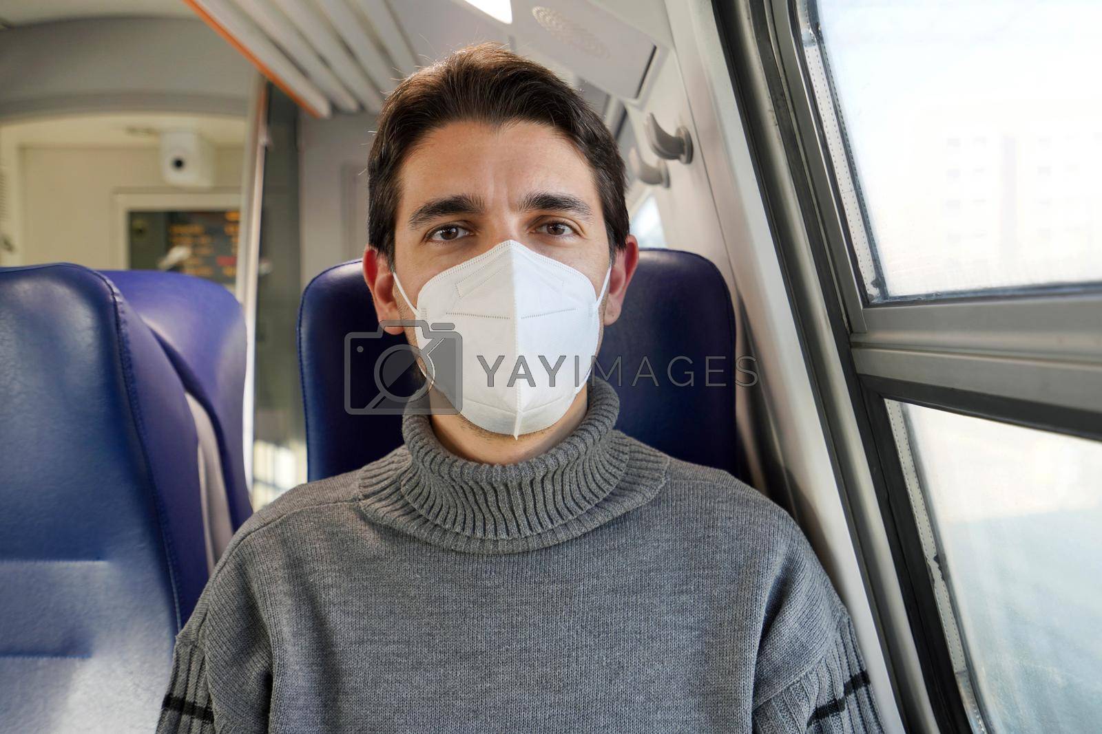Close up of male commuter wearing FFP2 KN95 protective mask on train looking at camera