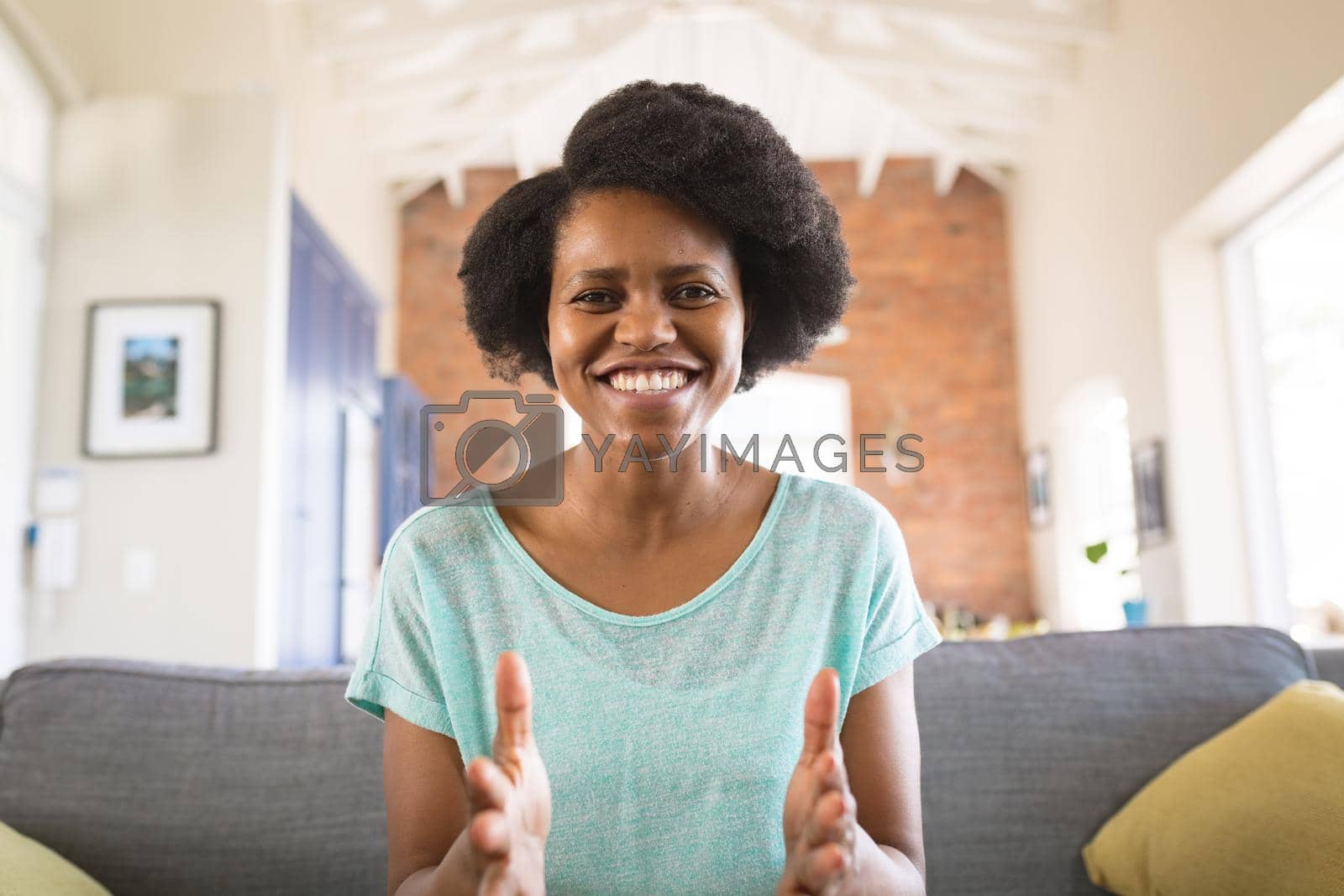 Royalty free image of Portrait of cheerful african american woman gesturing while explaining on video call at home by Wavebreakmedia