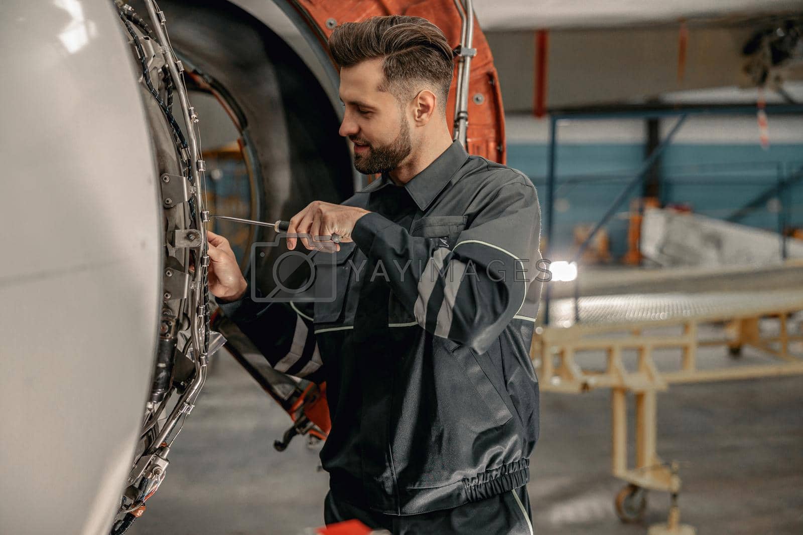Royalty free image of Male aviation mechanic repairing aircraft in hangar by Yaroslav_astakhov