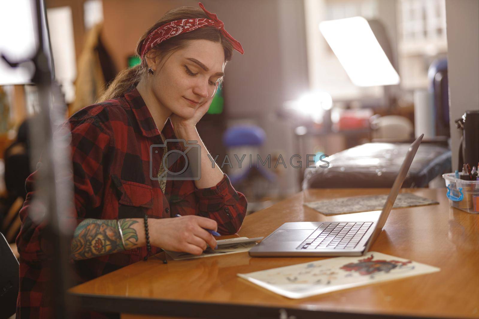 Royalty free image of Tattoo artist in plaid shirt making sketches, working on new pattern by Yaroslav_astakhov